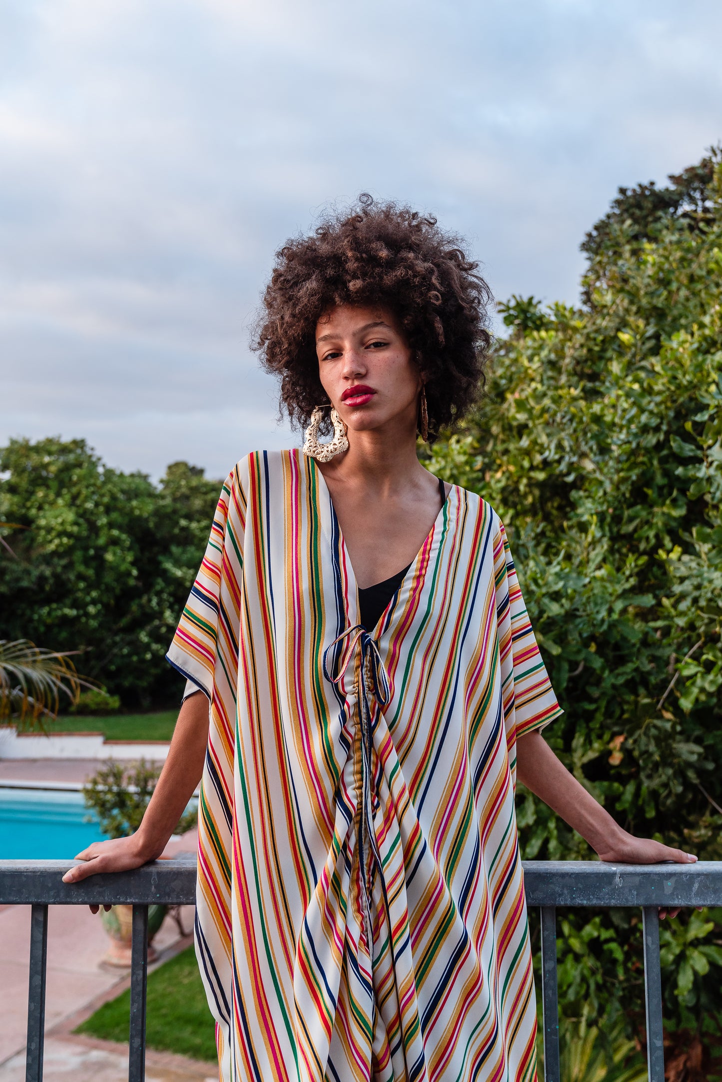 Multicolor vertical stripes on ivory chiffon caftan. This piece features a deep v-neck, batwing sleeve, a center drawstring for ruche styling, and ankle length hem. Retro bohemian aesthetic.