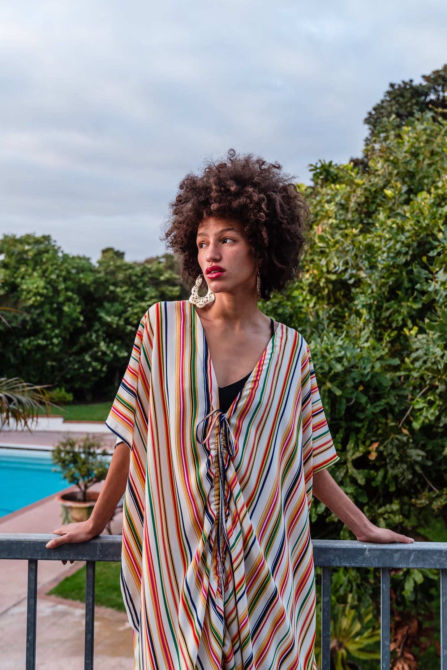 Multicolor vertical stripes on ivory chiffon caftan. This piece features a deep v-neck, batwing sleeve, a center drawstring for ruche styling, and ankle length hem. Retro bohemian aesthetic.