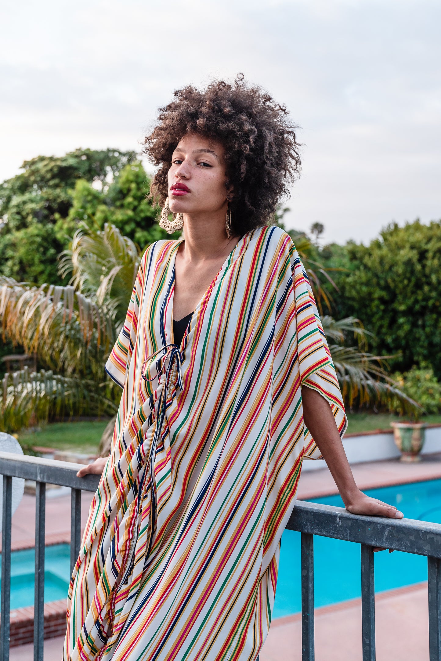 Multicolor vertical stripes on ivory chiffon caftan. This piece features a deep v-neck, batwing sleeve, a center drawstring for ruche styling, and ankle length hem. Retro bohemian aesthetic.