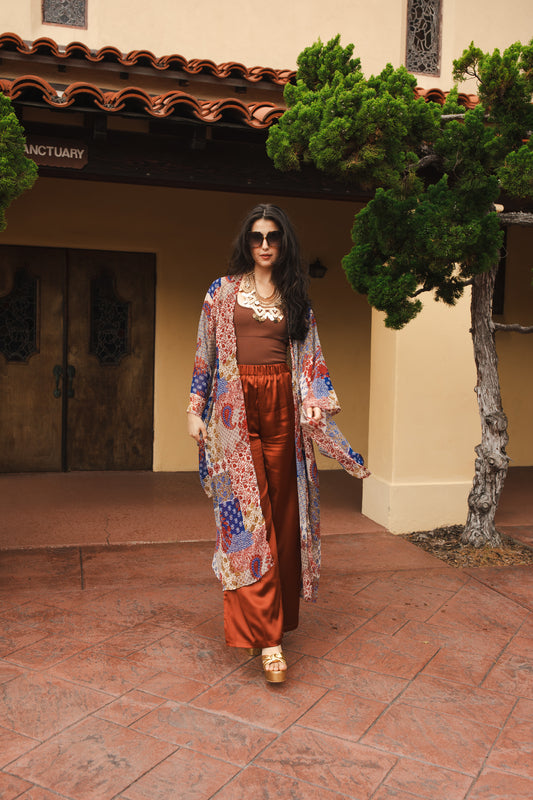 Long sleeve kimono with ankle length hem is made from a soft semi-sheer rayon chiffon. Featuring a paisley boho pattern in a mixture of red, blue, tan, and yellow. It also features pockets and a matching waist tie-you can style this piece in at least 10 ways.