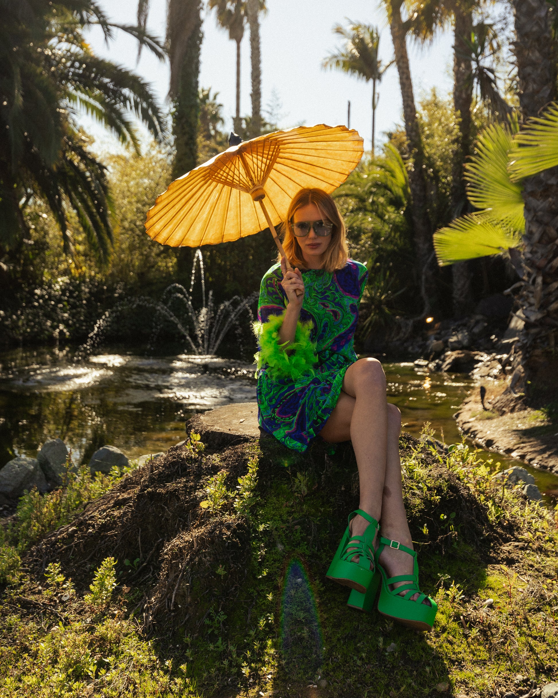 Funky fresh retro midi dress with royal blue and lime green abstract filigree swirl print with hints of aqua and fuchsia. The dress features a crew neck, keyhole detail at upper back, 3/4 bell sleeves with neon green feathers at cuff, a knee-length hem, and optional wrap tie for a cinched waist.