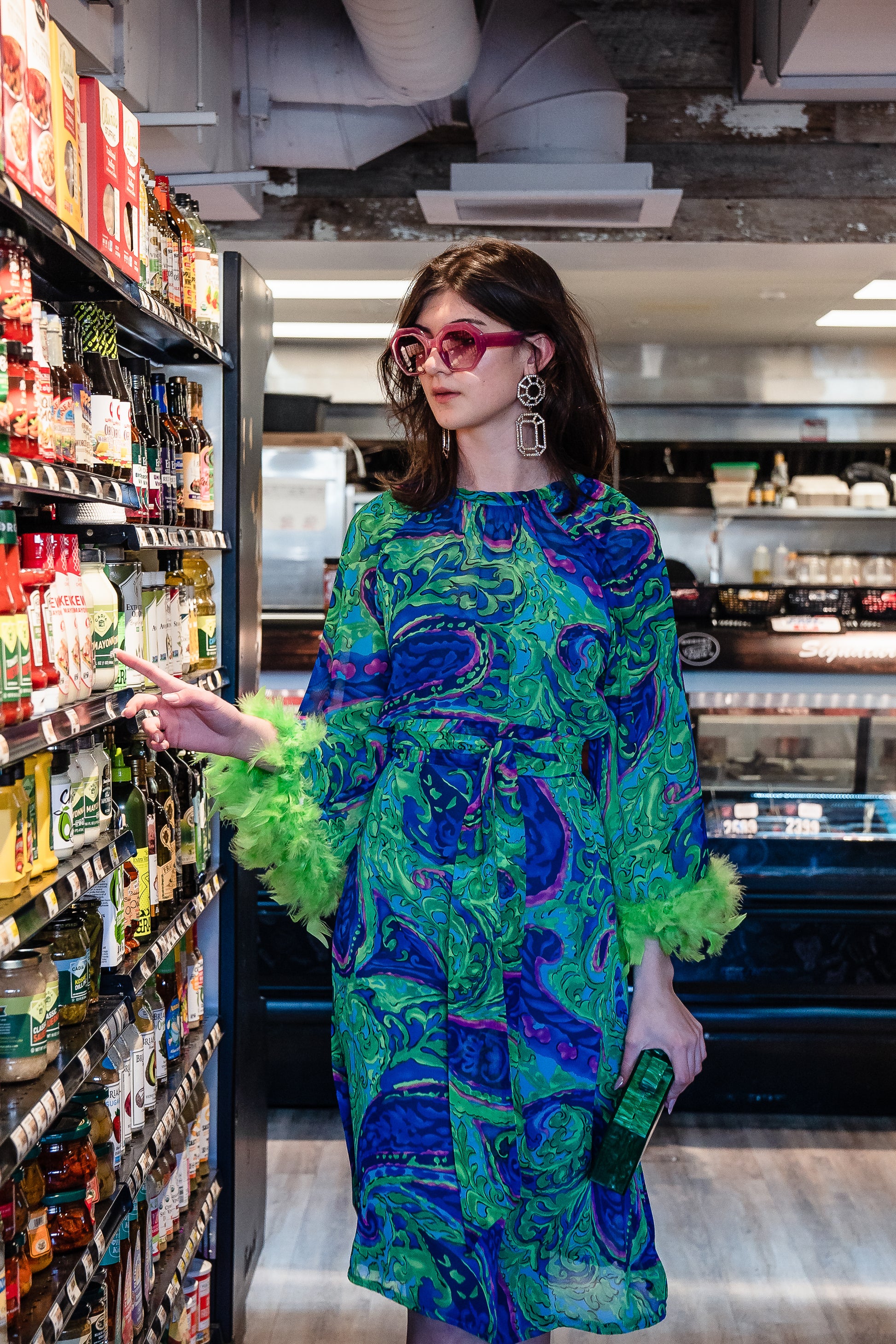 Funky fresh retro midi dress with royal blue and lime green abstract filigree swirl print with hints of aqua and fuchsia. The dress features a crew neck, keyhole detail at upper back, 3/4 bell sleeves with neon green feathers at cuff, a knee-length hem, and optional wrap tie for a cinched waist.