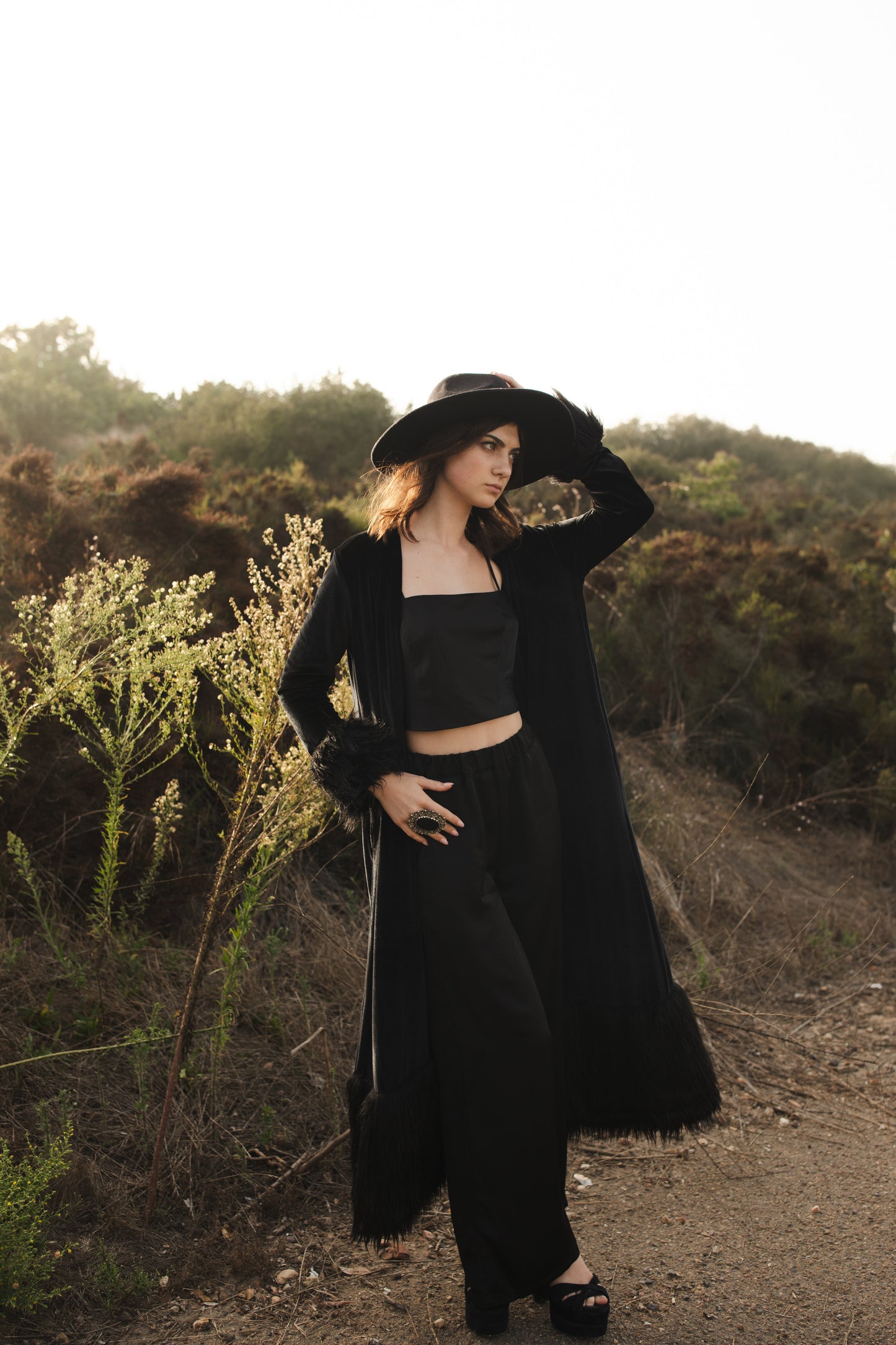 This luscious floor length Jennafer Grace coat is made with a black stretch velvet fabric featuring black faux fur cuffs at end of sleeves and base hem. It also features in-seam pockets and a super soft bamboo jersey lining. Designed and crafted in southern California.