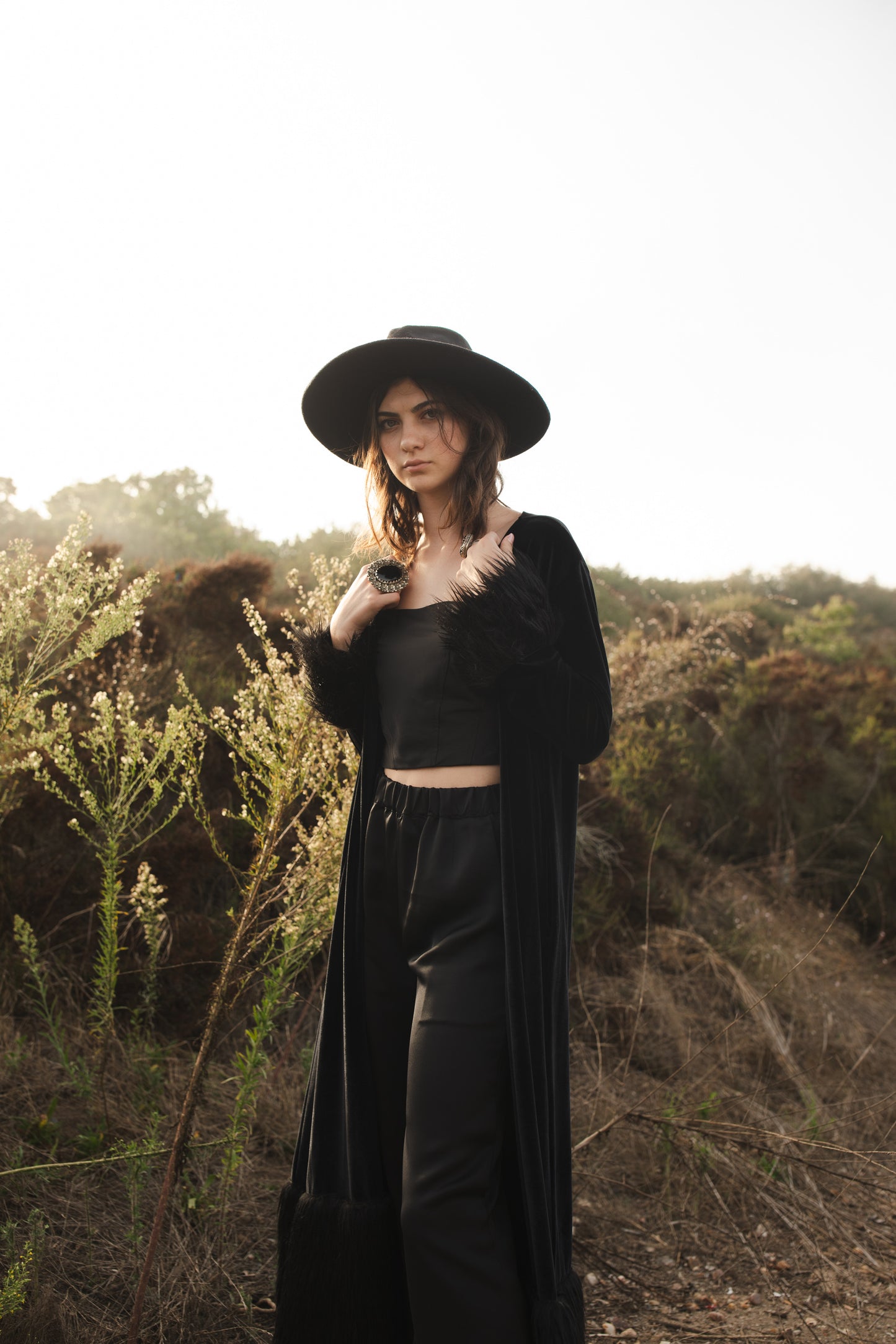 This luscious floor length Jennafer Grace coat is made with a black stretch velvet fabric featuring black faux fur cuffs at end of sleeves and base hem. It also features in-seam pockets and a super soft bamboo jersey lining. Designed and crafted in southern California.