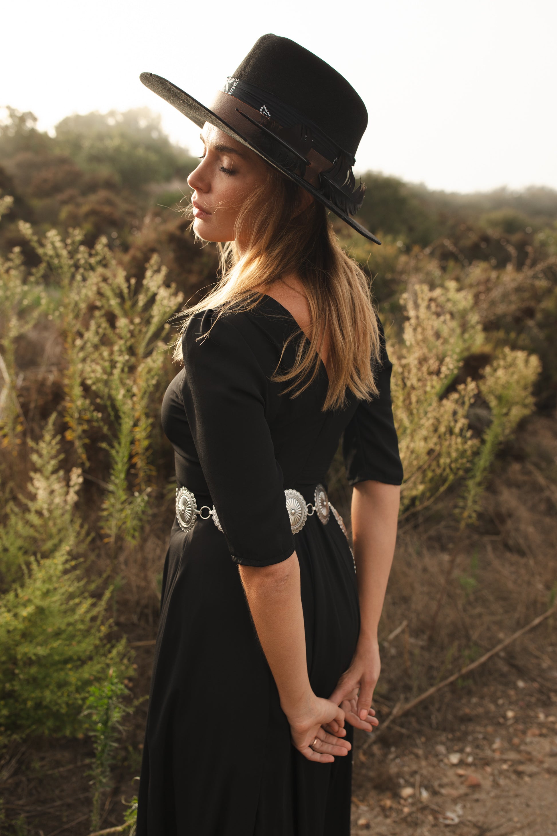 Jennafer Grace solid black maxi dress features princess seamed skirts and pockets. The dress has an invisible zipper and high/low neck options you can wear it multiple ways. Fitted torso with elbow length sleeves and ankle hem.