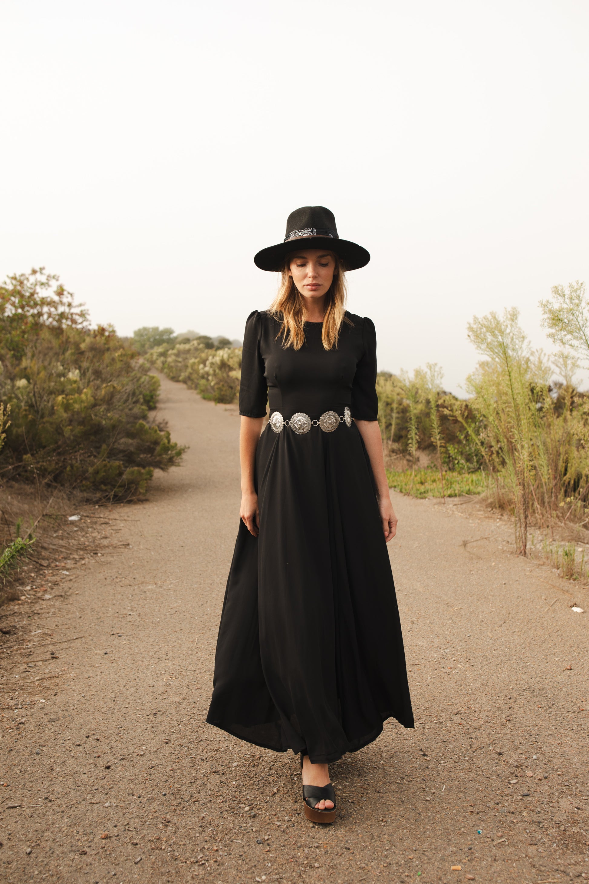 Jennafer Grace solid black maxi dress features princess seamed skirts and pockets. The dress has an invisible zipper and high/low neck options you can wear it multiple ways. Fitted torso with elbow length sleeves and ankle hem.