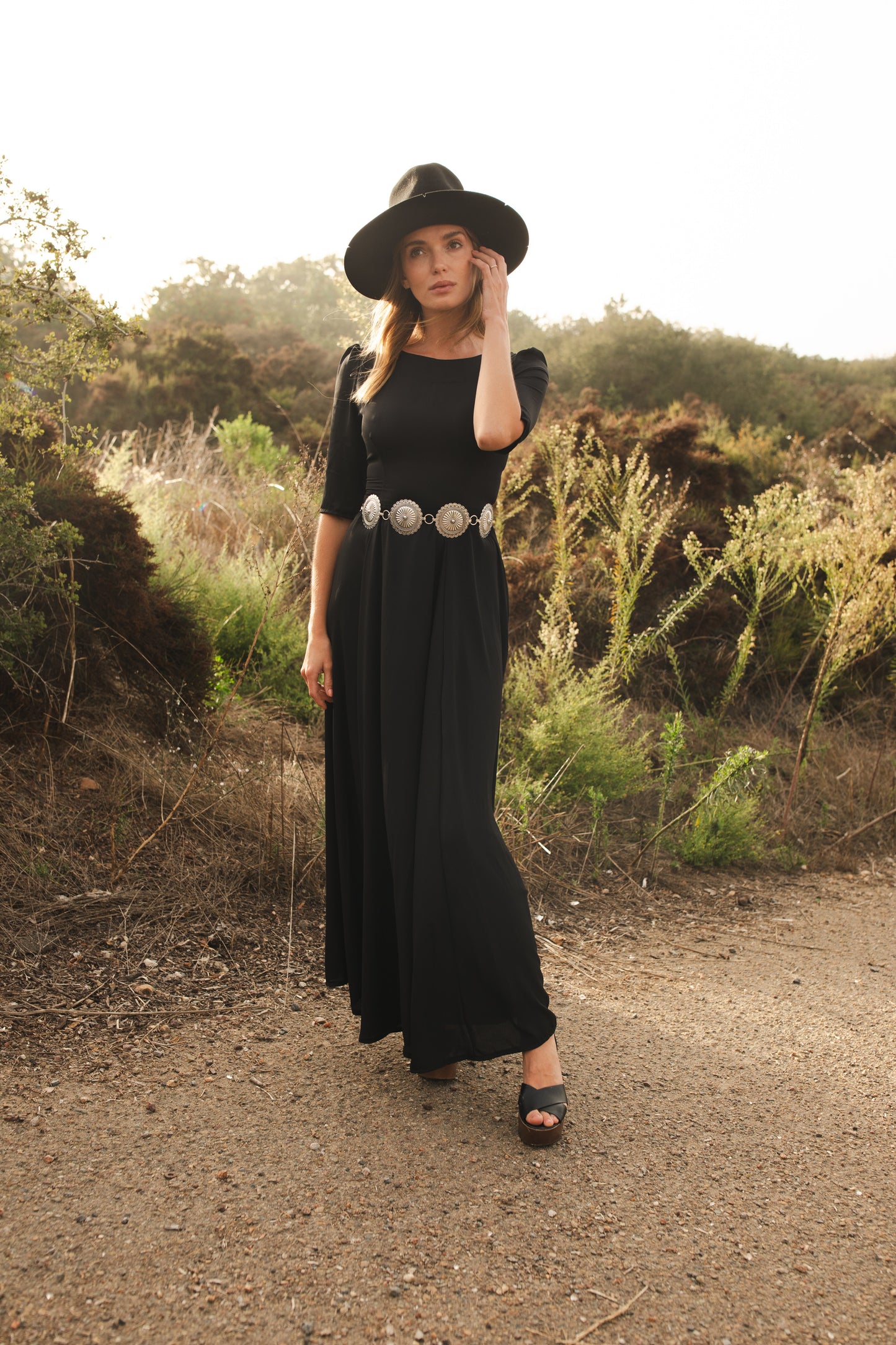 Jennafer Grace solid black maxi dress features princess seamed skirts and pockets. The dress has an invisible zipper and high/low neck options you can wear it multiple ways. Fitted torso with elbow length sleeves and ankle hem.