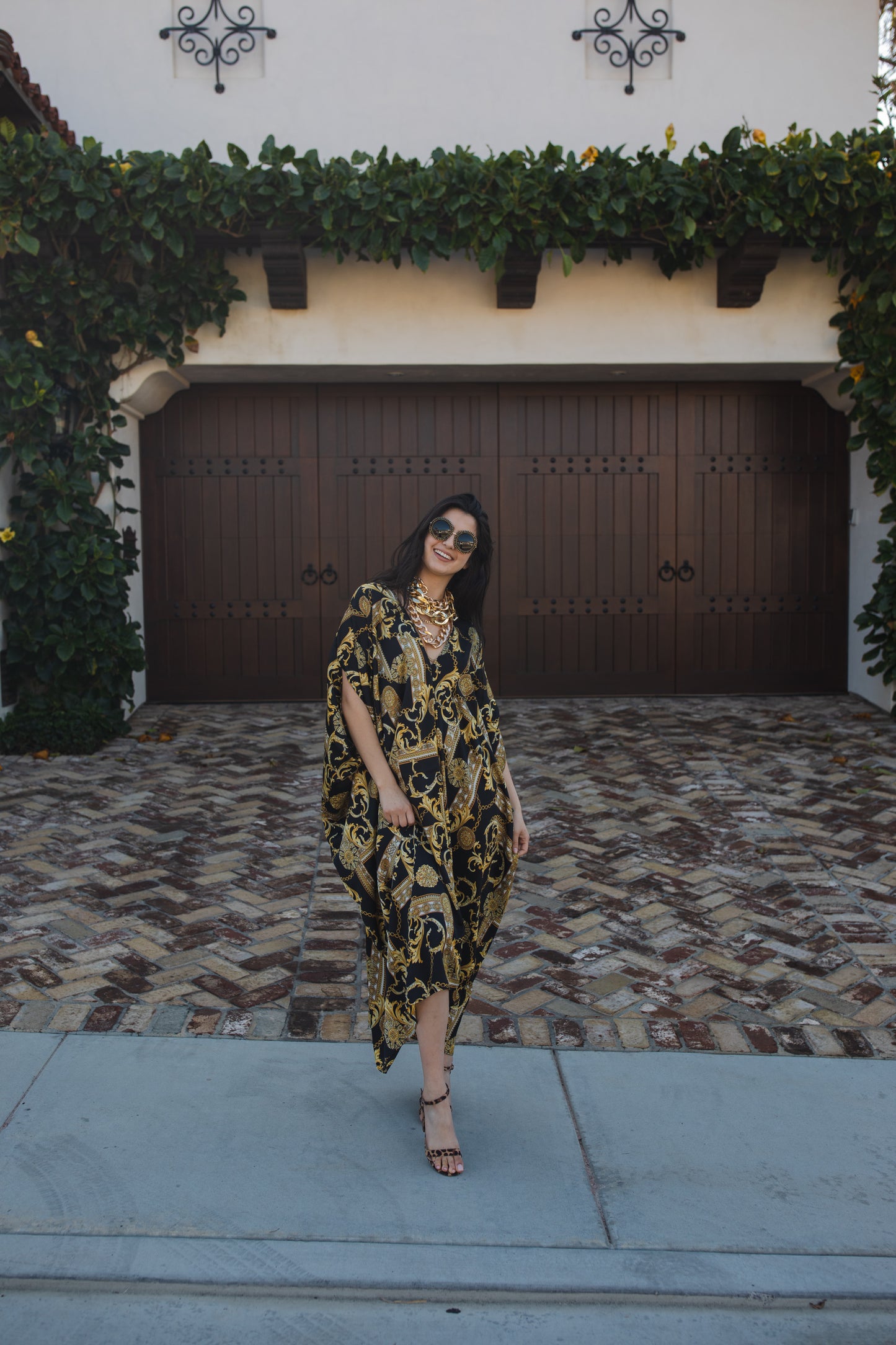 Opaque black caftan dress featuring yellow gold ornamental filigree patterned design. Featuring a deep v-neckline, short batwing sleeves, and an ankle-length hem. This caftan is a voluminous garment that gives a flowy silhouette that drapes beautifully on all shapes.