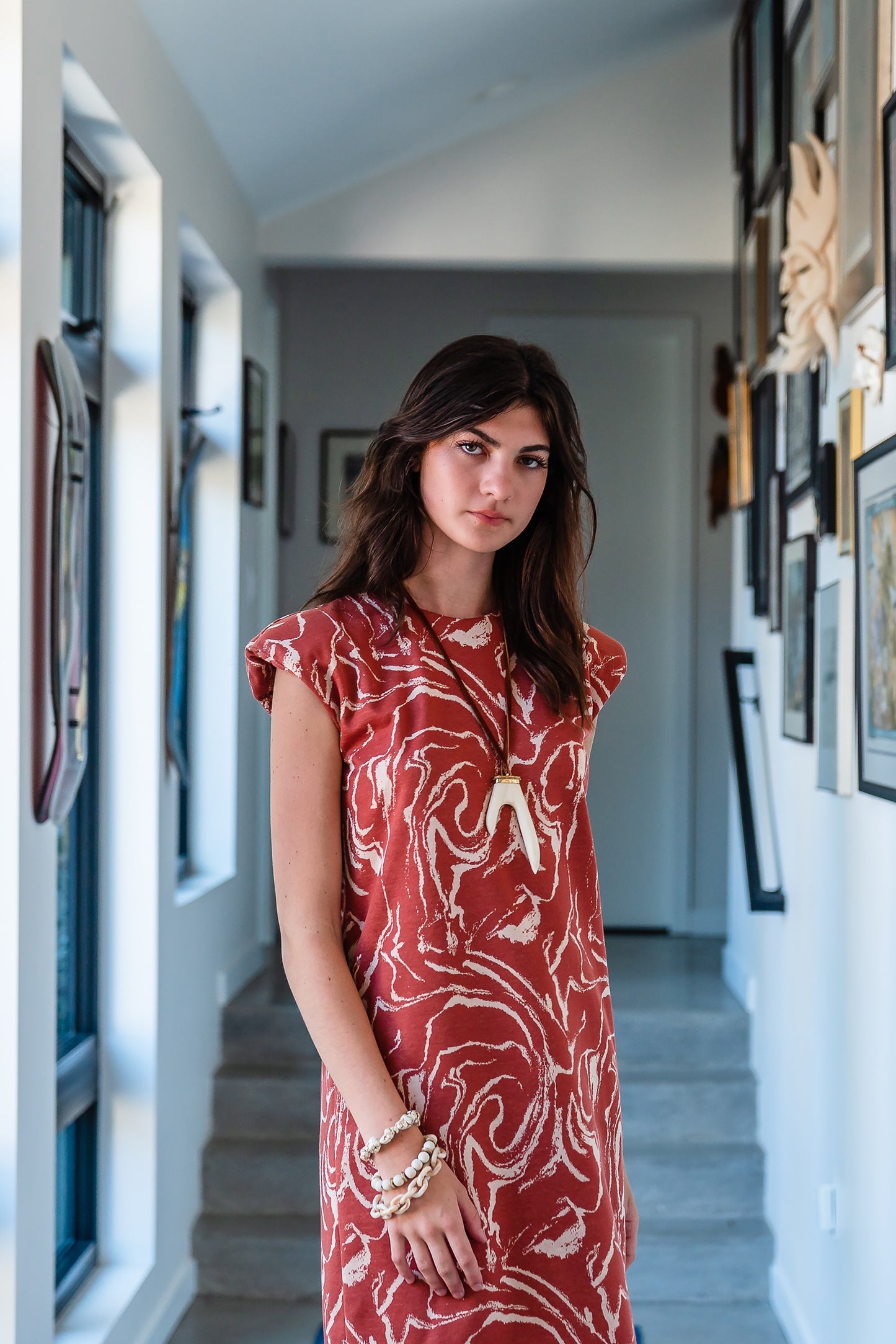 Knee length sleeveless shift dress, in a rust and taupe abstract, marble like pattern, the dress has shoulder pads.