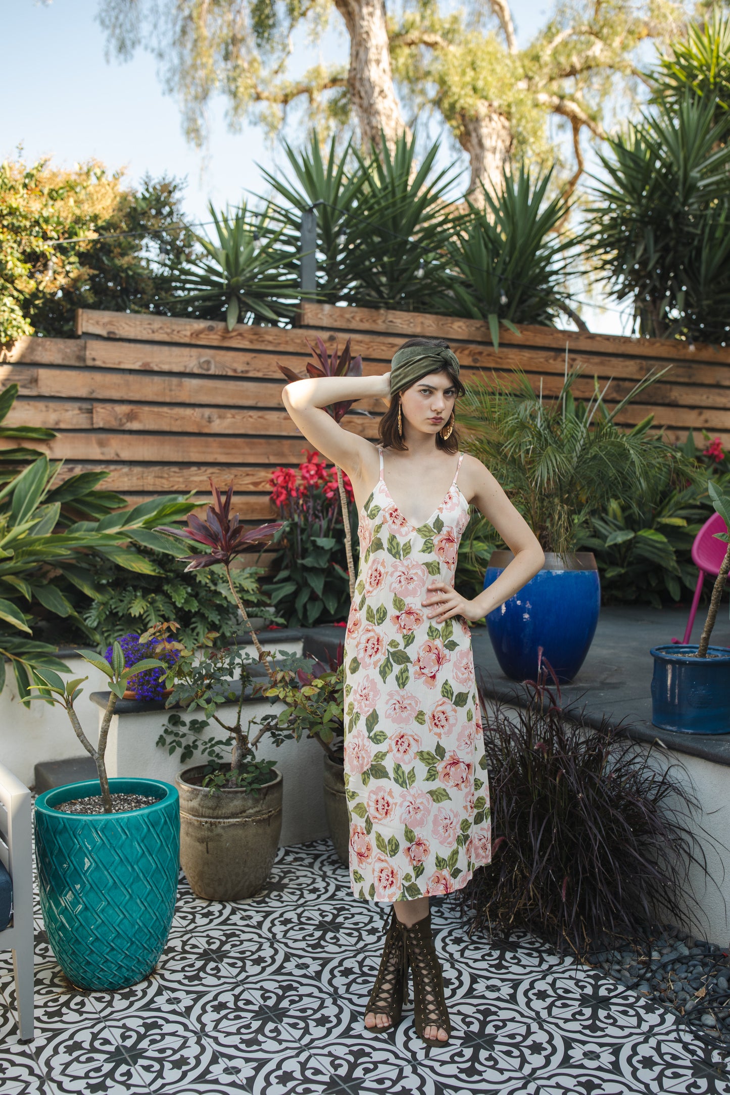 Midi slip dress with an ivory base color, adorned with floral rose print pattern featuring shades of green and pink. It features slender straps with a straight silhouette and relaxed fix, allowing for a beautiful drape and flowy movement. It's designed for a light, airy feel, suitable for warm weather or layered for cooler days.