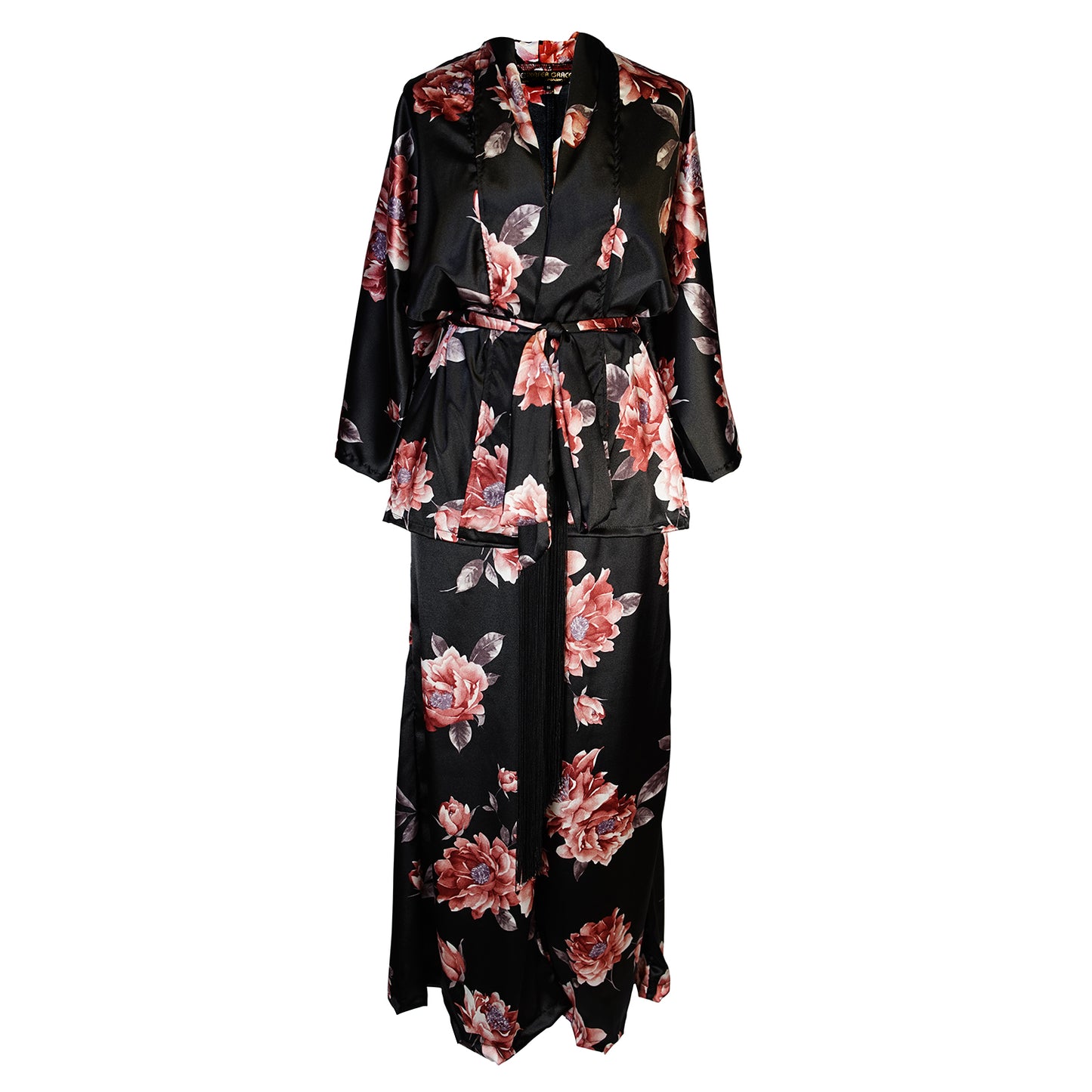 Loungewear set in dark floral pattern. A black background with light pink flowers, this set comes with a wrap dolman jacket.  Sleeves have a forearm hem, and it can be worn as an open jacket or wrap with matching tie belt. The belt features fringe tassels. The matching pants have pockets and an ankle length hem. 