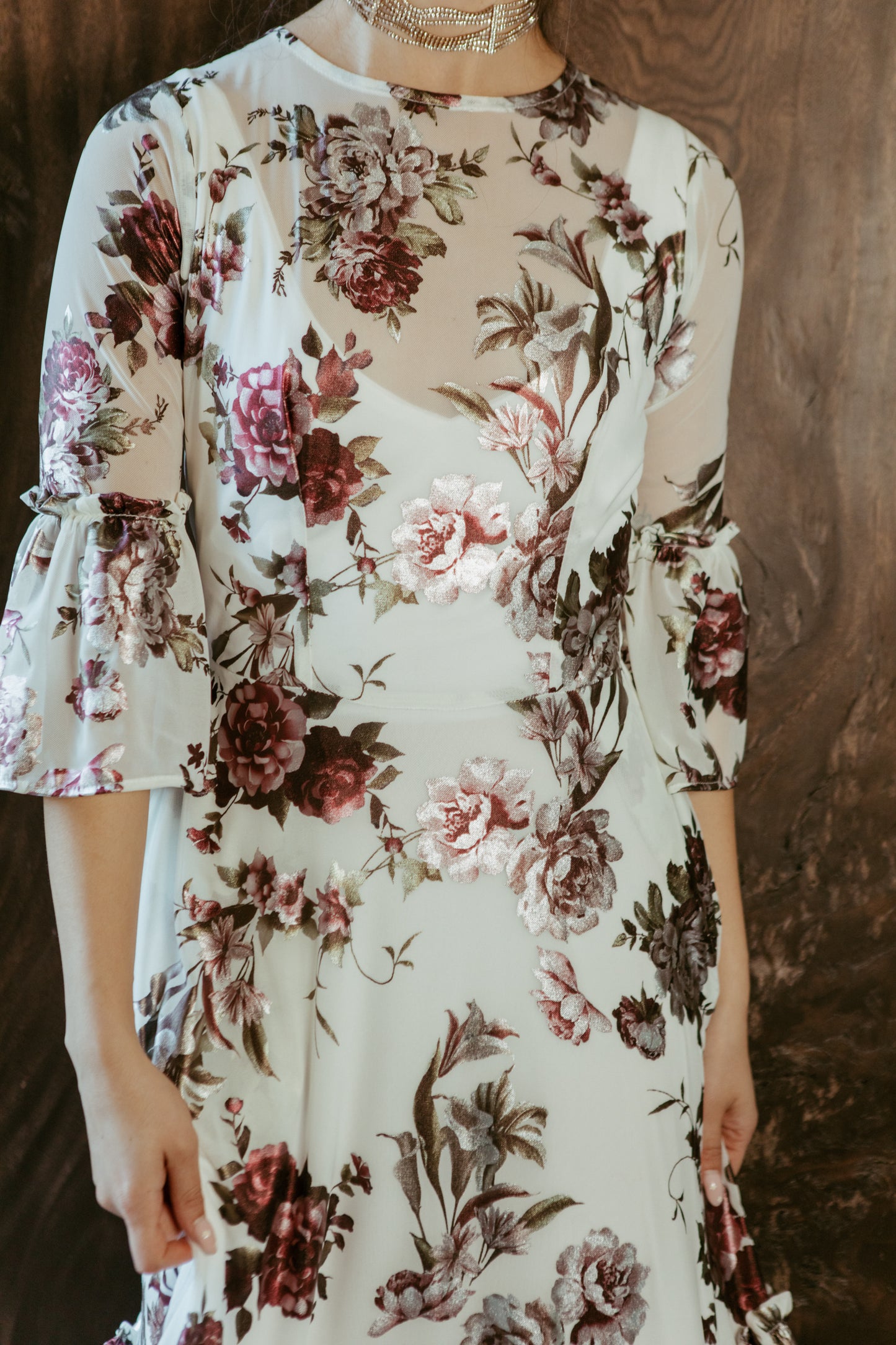 An airy ruffled maxi dress. Made with an airy and metallic detail floral mesh fabric featuring pockets, mid-length bell sleeves, and a full, single-tiered skirt with ankle hem. Includes a matching slip dress that can be worn on its own.