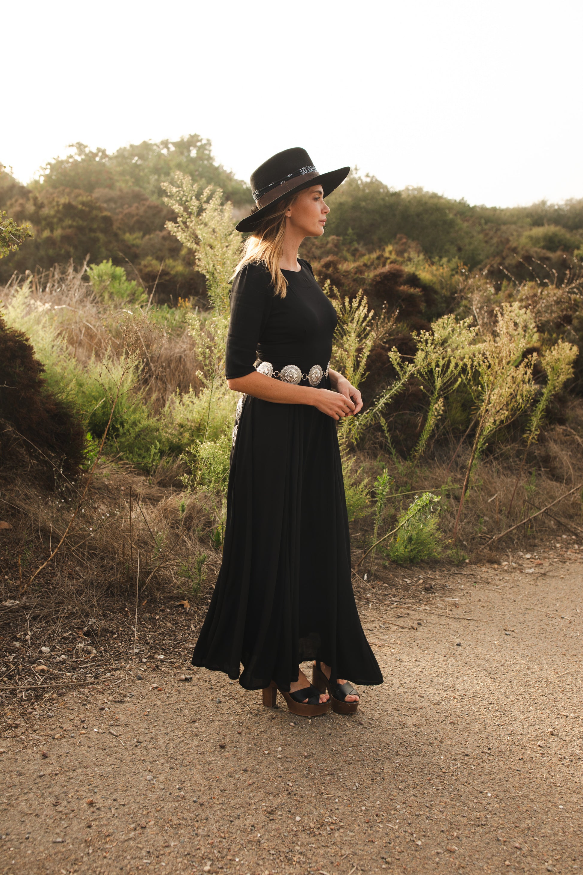 Jennafer Grace solid black maxi dress features princess seamed skirts and pockets. The dress has an invisible zipper and high/low neck options you can wear it multiple ways. Fitted torso with elbow length sleeves and ankle hem.