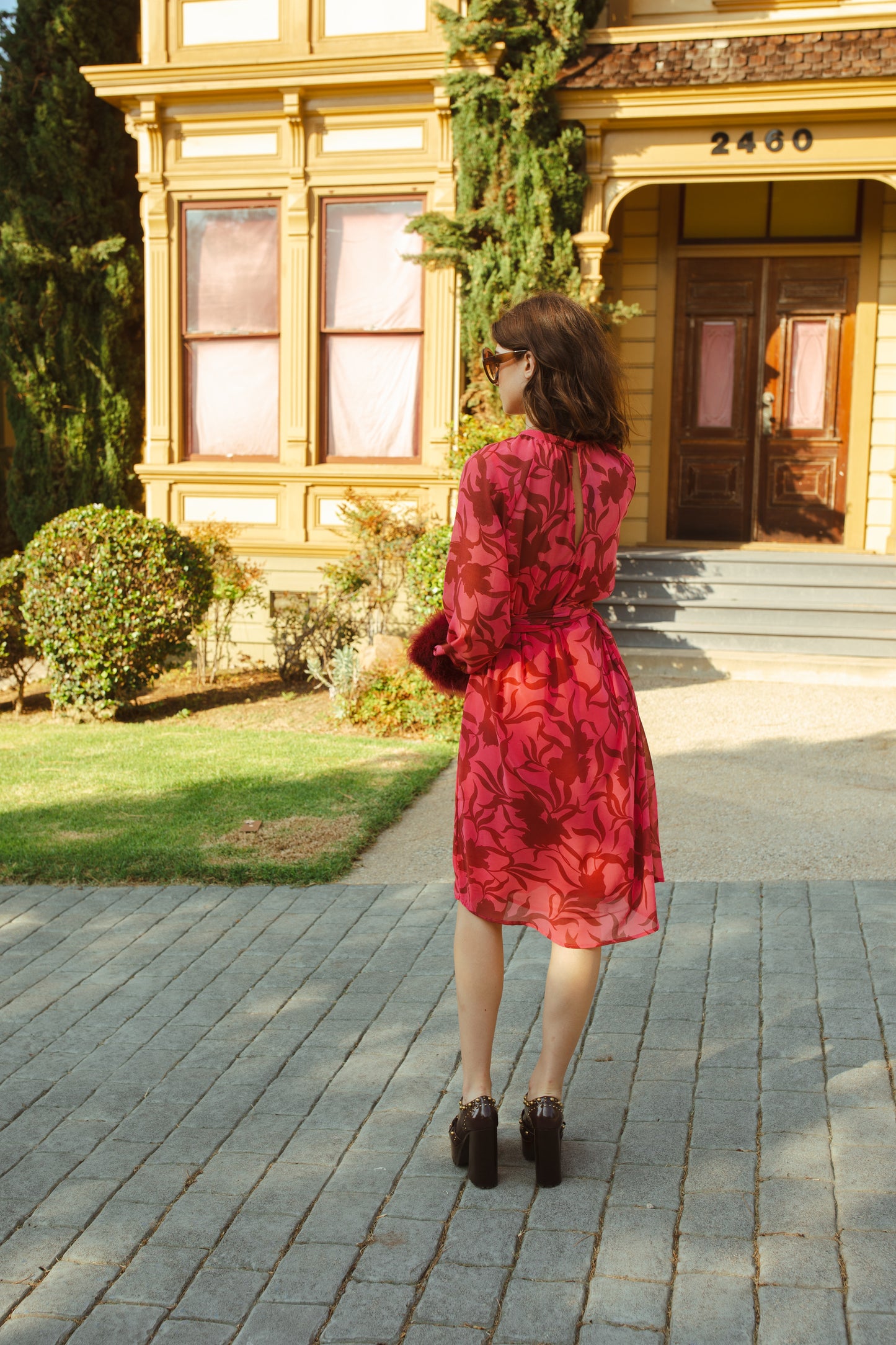 This sophisticated stunner has all the right details - generous bell sleeves with feather detail, flowing knee-length midi skirt, and a slim matching sash for a cinched waist.