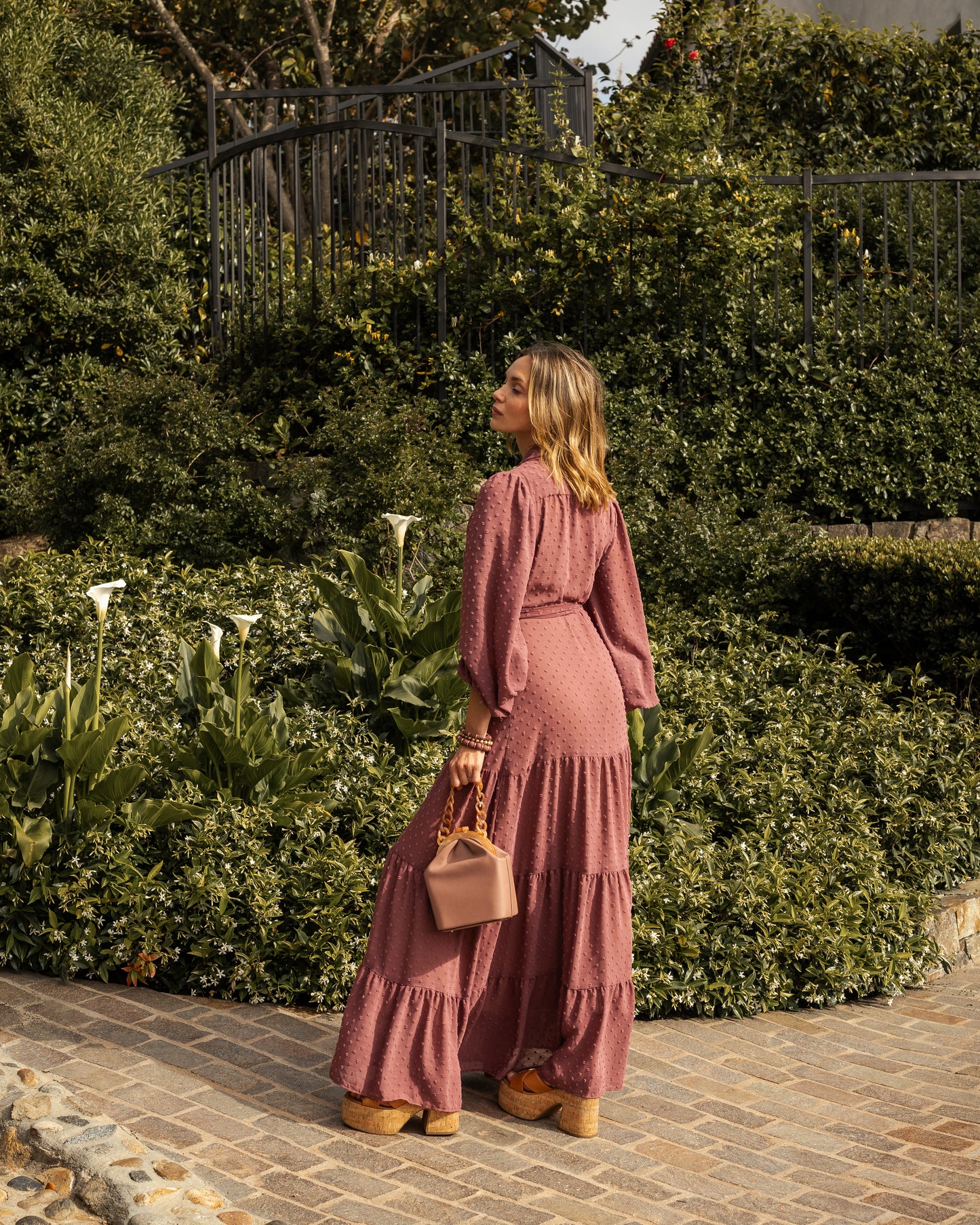 This Swiss Dot maxi dress is sophisticated yet effortless with its high collar, button-up design paired with bishop sleeves, tiered skirt, and a slim matching sash.