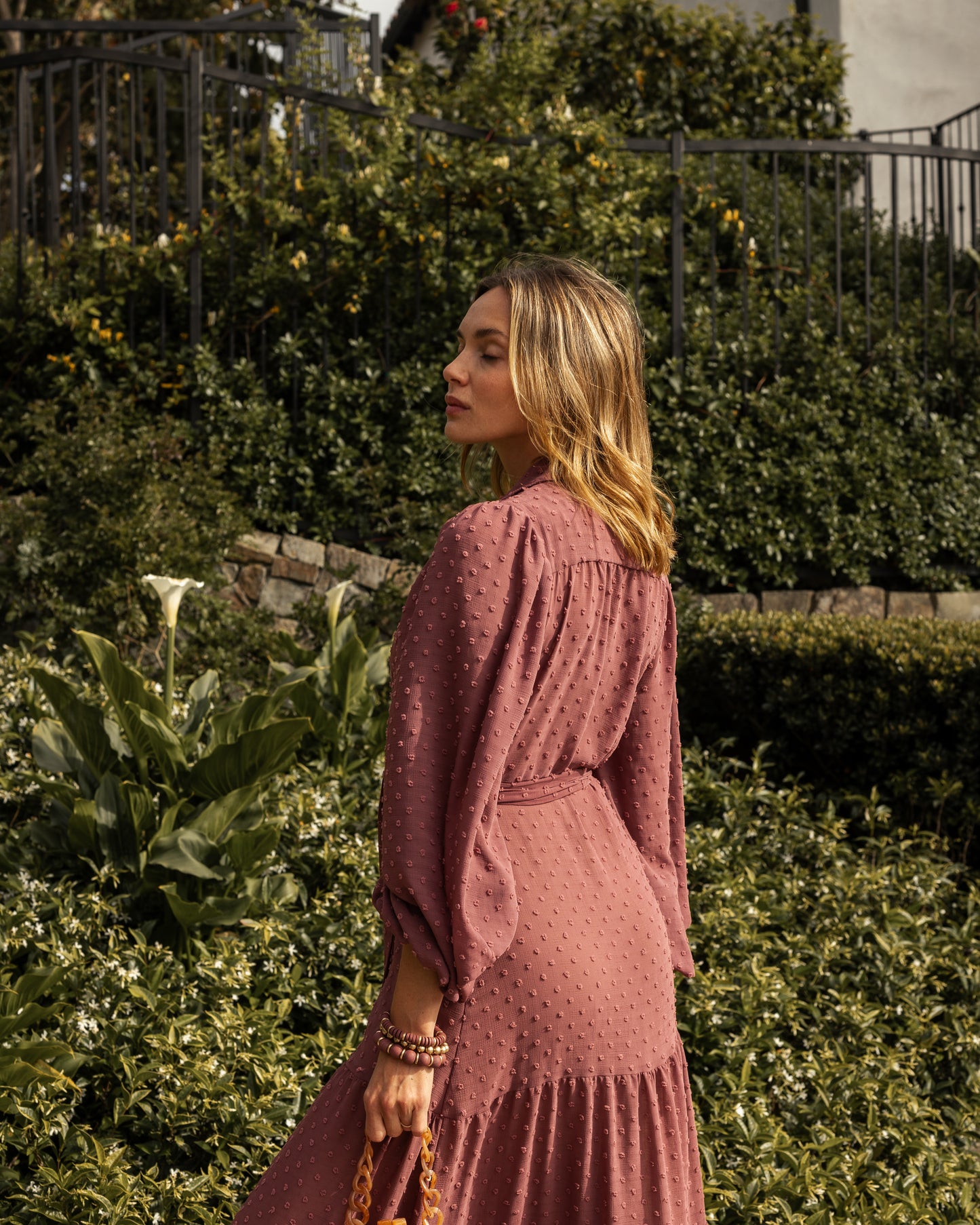 This Swiss Dot maxi dress is sophisticated yet effortless with its high collar, button-up design paired with bishop sleeves, tiered skirt, and a slim matching sash.