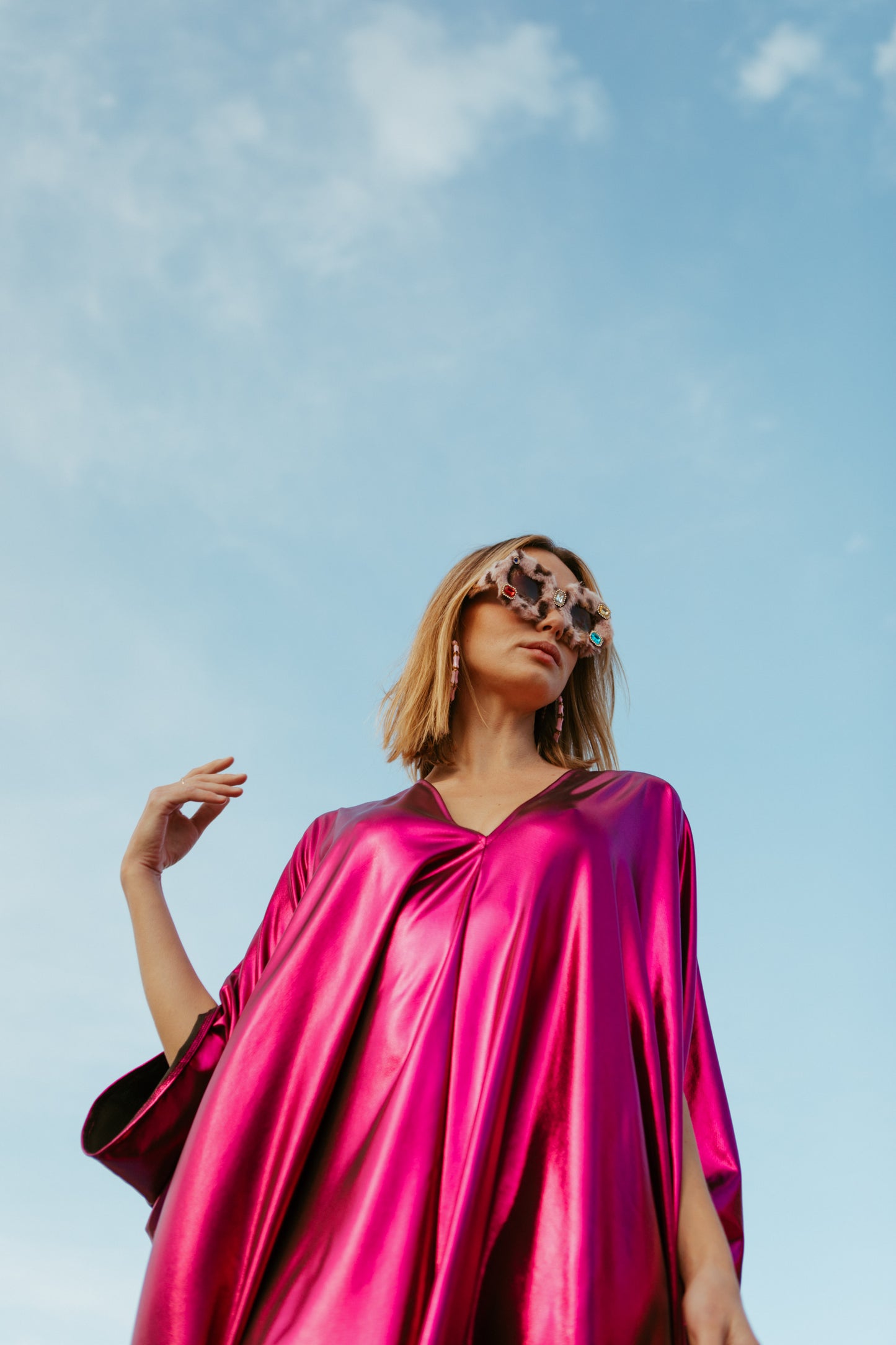 Bold, metallic caftan crafted from a slinky black jersey coated with a deep fuchsia foil that shimmers in the light. The caftan has a generous, free-flowing cut, with ample fabric creating an elegant, loose fit that drapes comfortably over the body, with batwing sleeves and a deep v-neckline.