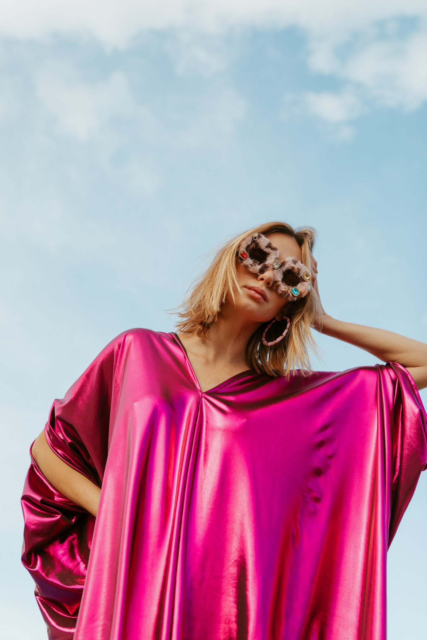 Bold, metallic caftan crafted from a slinky black jersey coated with a deep fuchsia foil that shimmers in the light. The caftan has a generous, free-flowing cut, with ample fabric creating an elegant, loose fit that drapes comfortably over the body, with batwing sleeves and a deep v-neckline.