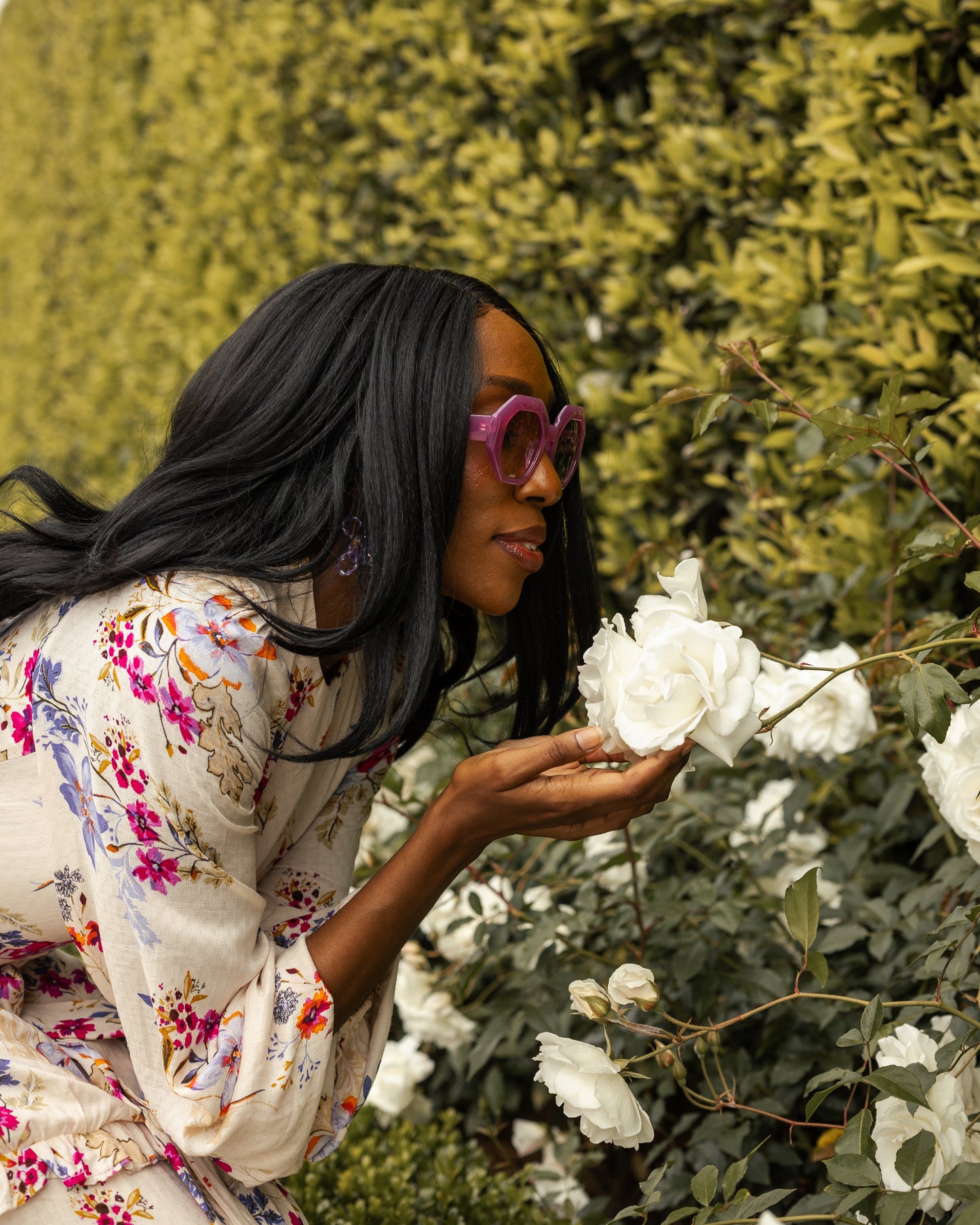 A floral maxi dress made from a soft, linen like crepe, it features high neck, bishop sleeves, tiered ruffle skirt and matching sash for a cinched waist. It's light, airy silhouette. Base color is pale yellow with a mixture of fuchsia, orange, and blue flowers as the print.