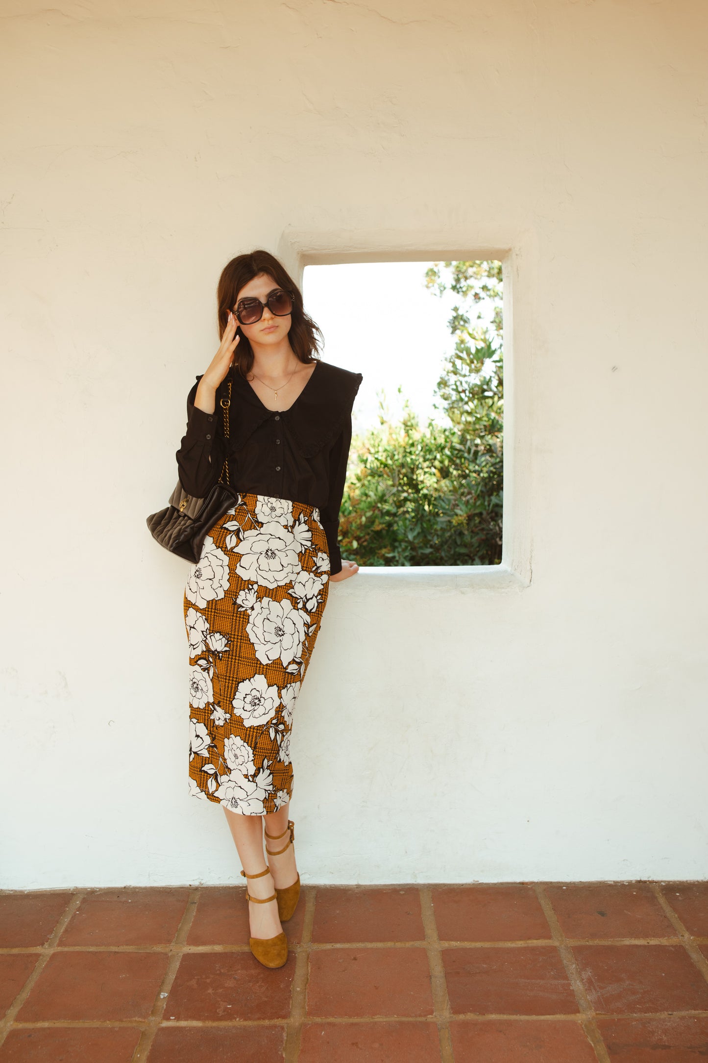 Cognac brown midi pencil skirt featuring black houndstooth pattern overlaid with large, modern, white and black floral print. This skirt is below the knee in length with an elastic waist for comfort. Bohemian floral meets dark academia in style.