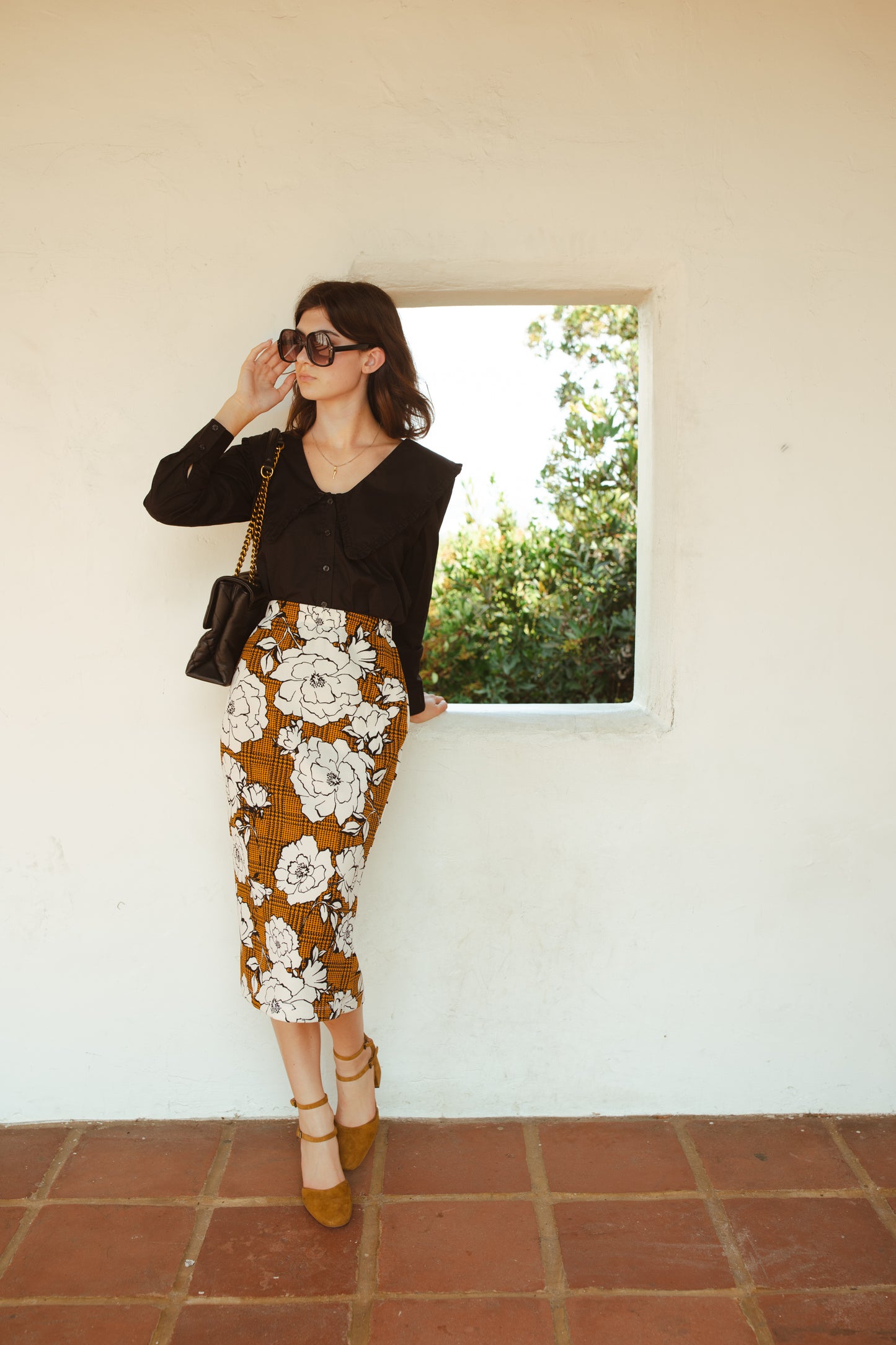 Cognac brown midi pencil skirt featuring black houndstooth pattern overlaid with large, modern, white and black floral print. This skirt is below the knee in length with an elastic waist for comfort. Bohemian floral meets dark academia in style.