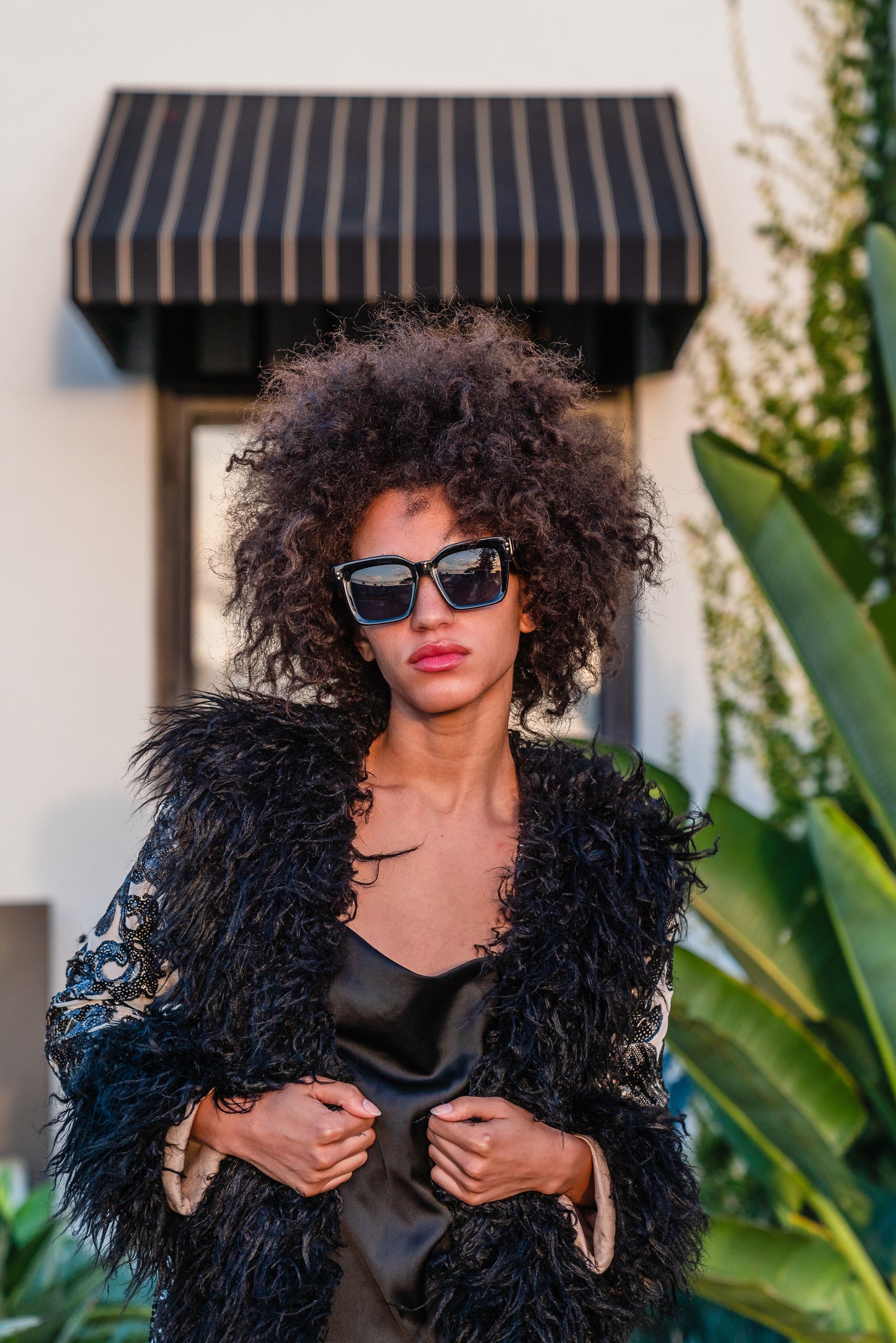 A floor length coat made of nude mesh with black sequins in a floral patter. The coat is lined around the collar, down the opening and around the hem in fluffy black faux alpaca fur, the coat has pockets and a nude colored lining of bamboo jersey.