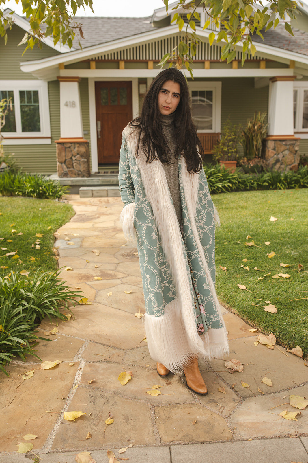 Long, penny lane style trench coat fashioned from a thick, mint green fabric embroidered with ivory snakes. Embellished with long ivory faux fur along collar, lapel, cuffs, and hem. Bohemian maximalism in style.