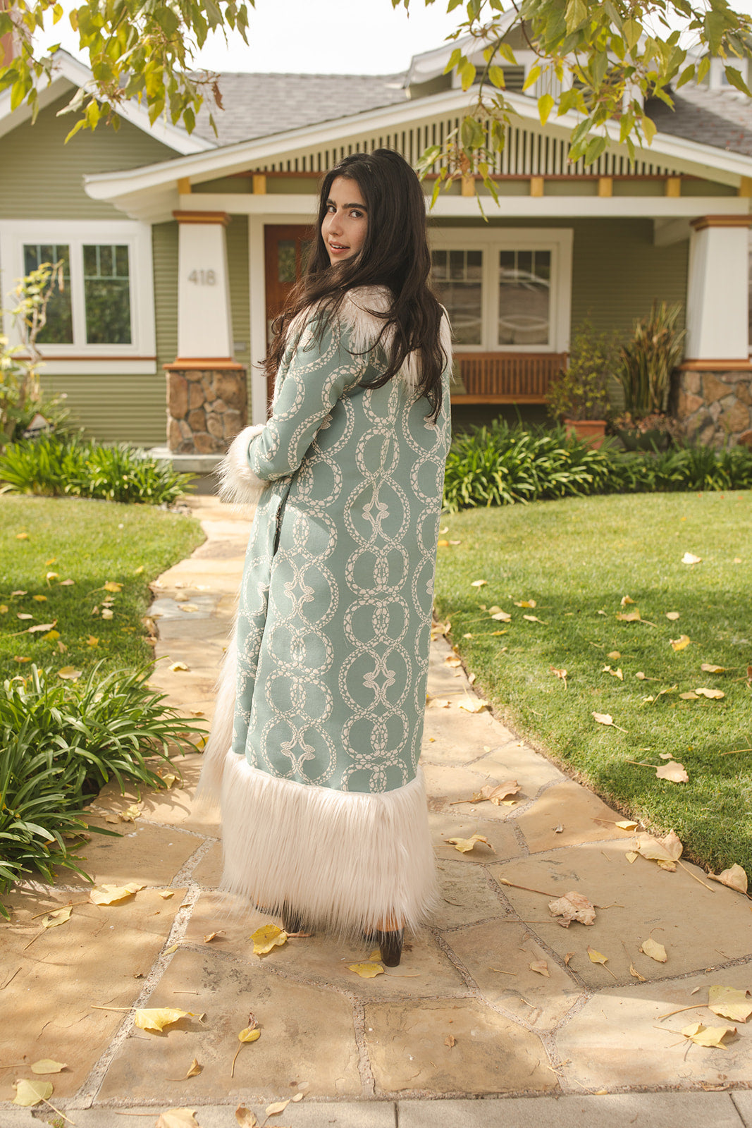 Long, penny lane style trench coat fashioned from a thick, mint green fabric embroidered with ivory snakes. Embellished with long ivory faux fur along collar, lapel, cuffs, and hem. Bohemian maximalism in style.