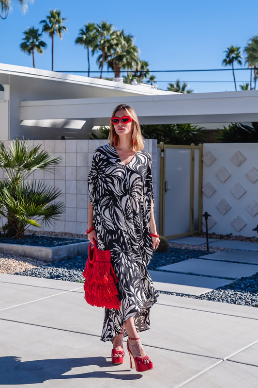  A versatile and flowy caftan in an abstract black and white floral print. This caftan features a deep v-neck, batwing sleeves, and ankle length hem.