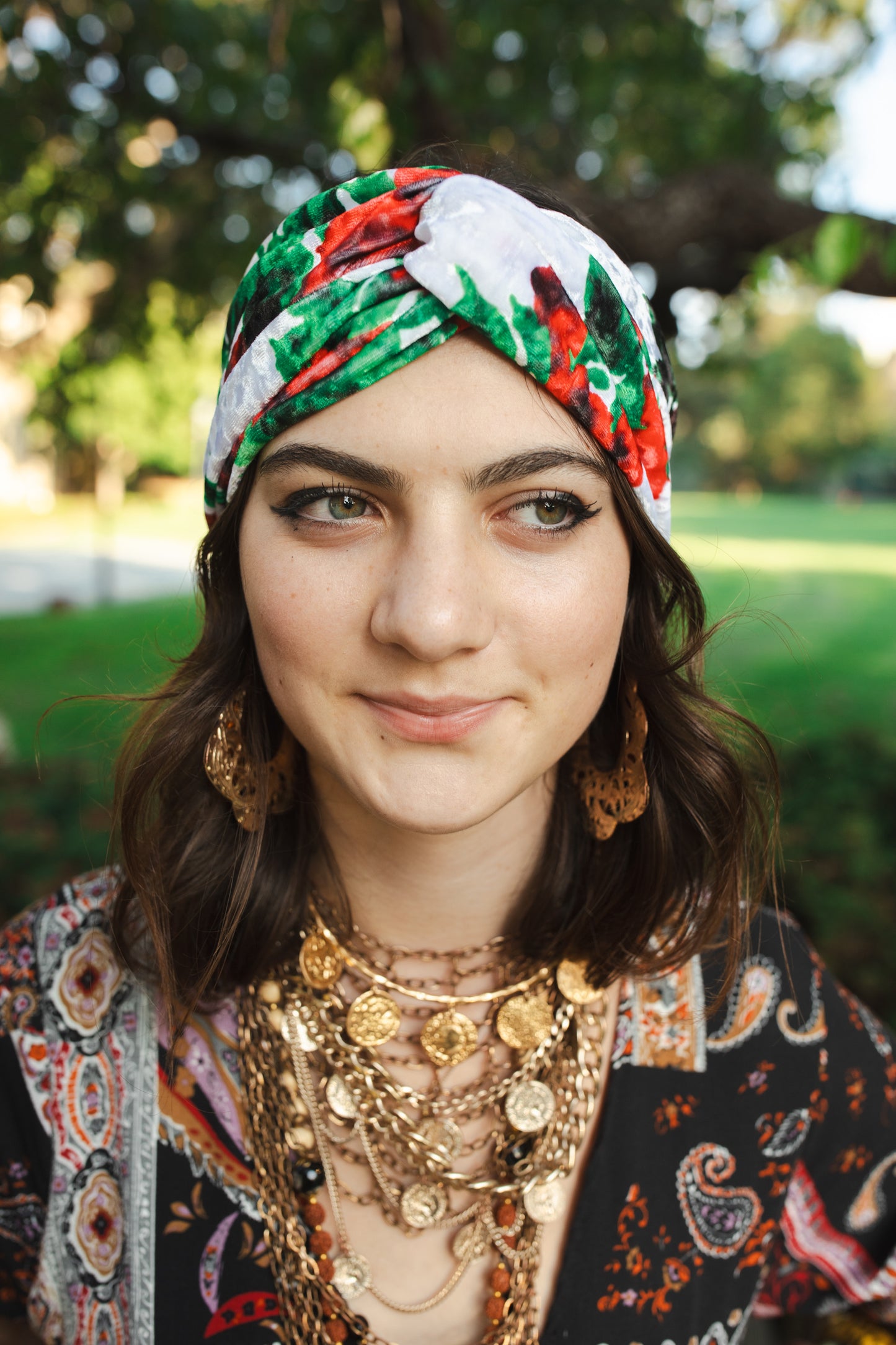 White, green, and red abstract floral print velvet headband with a front twist.