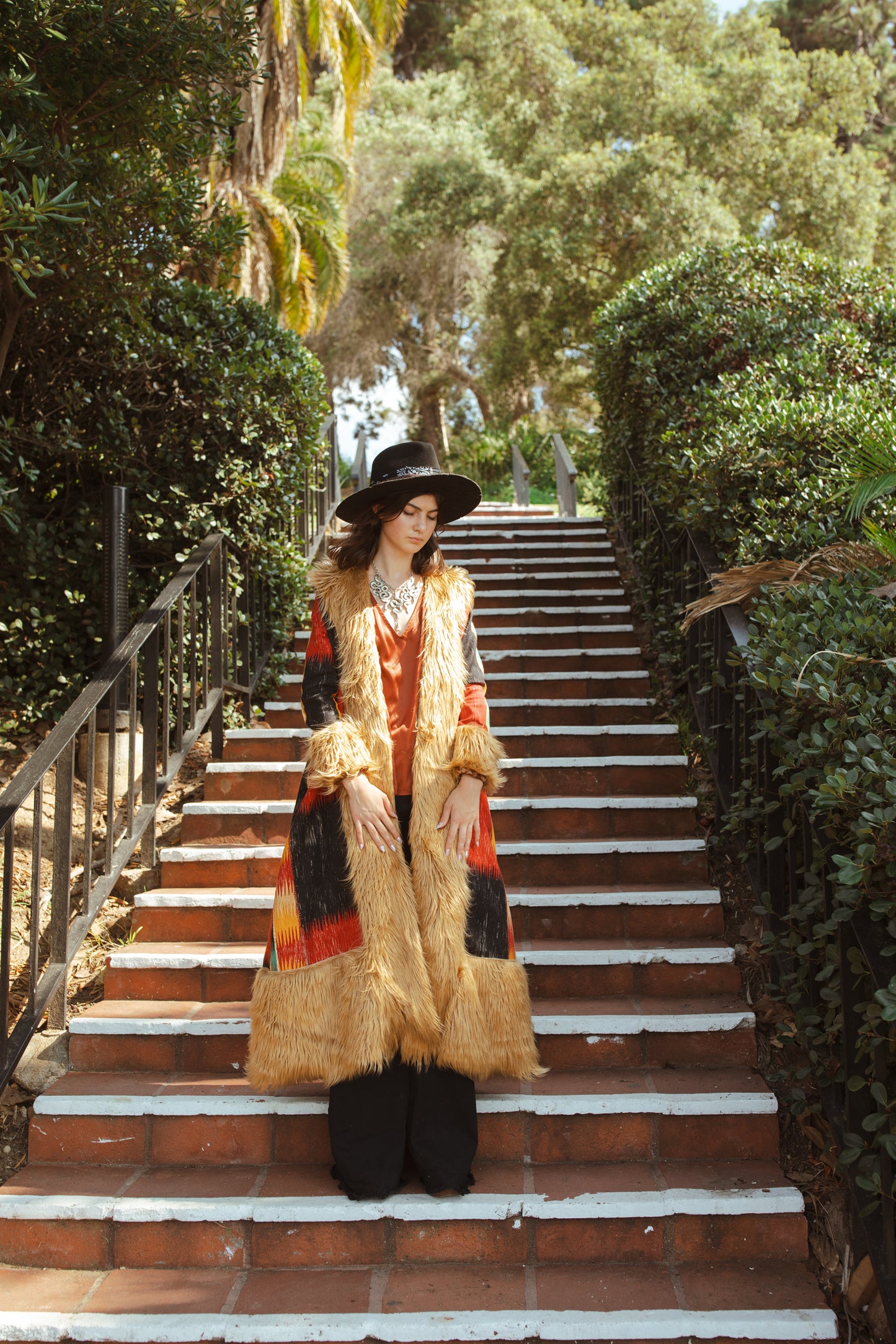 Long, penny lane style trench coat fashioned from a thick, abstract modernist colorblock print fabric featuring red, teal, yellow, black, and beige. Embellished with long tan faux fur along collar, lapel, cuffs, and hem. Retro bohemian color field art in style.