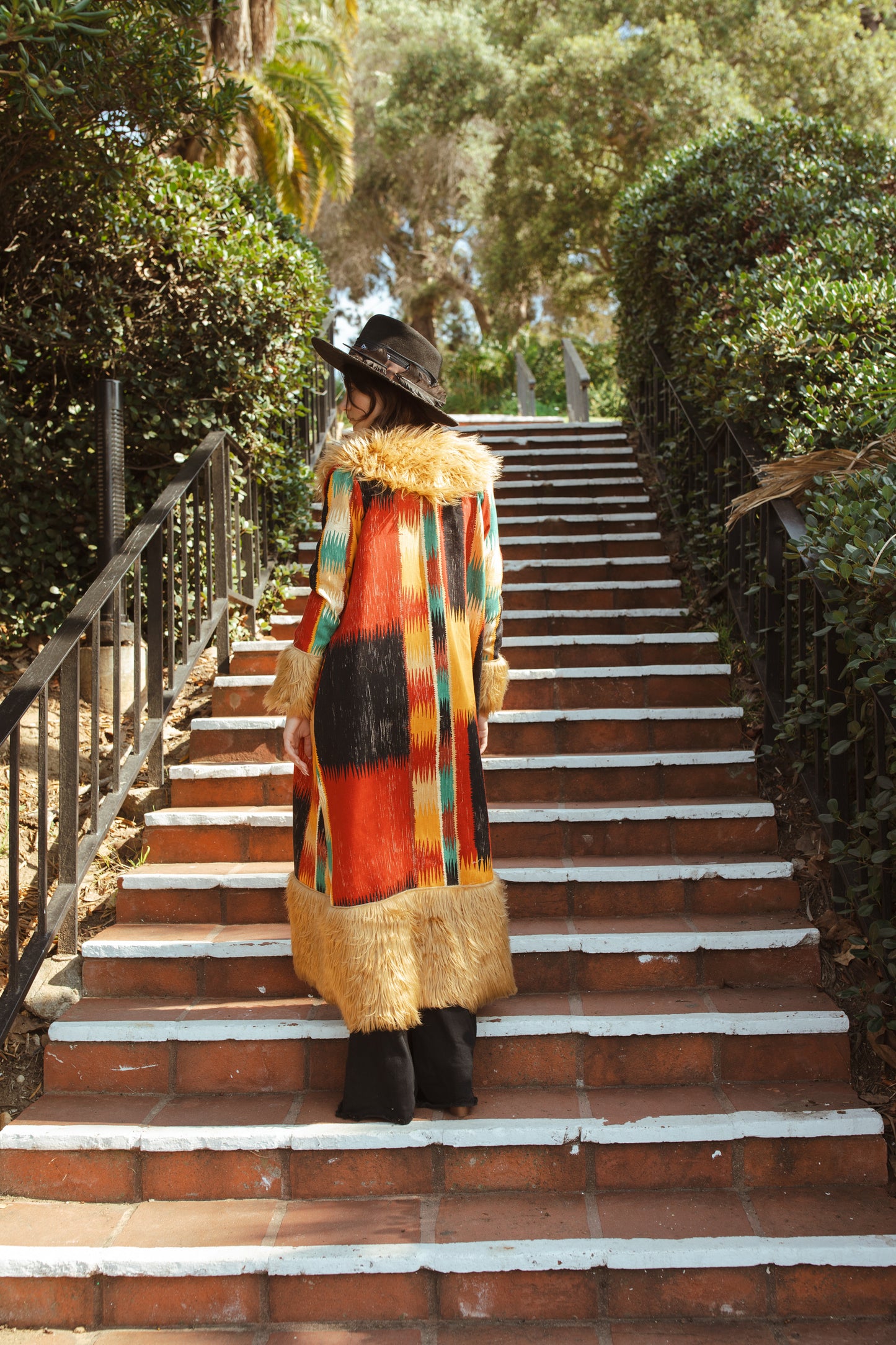 Long, penny lane style trench coat fashioned from a thick, abstract modernist colorblock print fabric featuring red, teal, yellow, black, and beige. Embellished with long tan faux fur along collar, lapel, cuffs, and hem. Retro bohemian color field art in style.