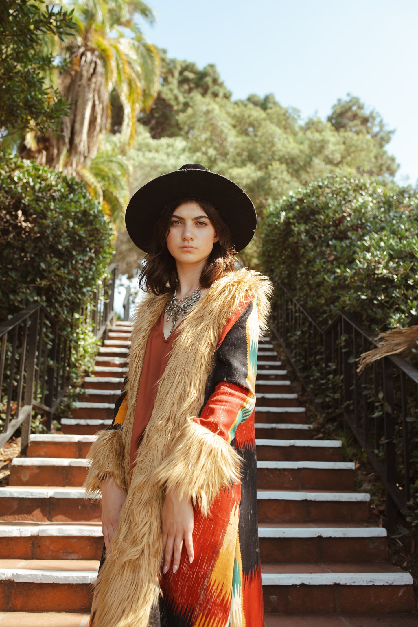 Long, penny lane style trench coat fashioned from a thick, abstract modernist colorblock print fabric featuring red, teal, yellow, black, and beige. Embellished with long tan faux fur along collar, lapel, cuffs, and hem. Retro bohemian color field art in style.