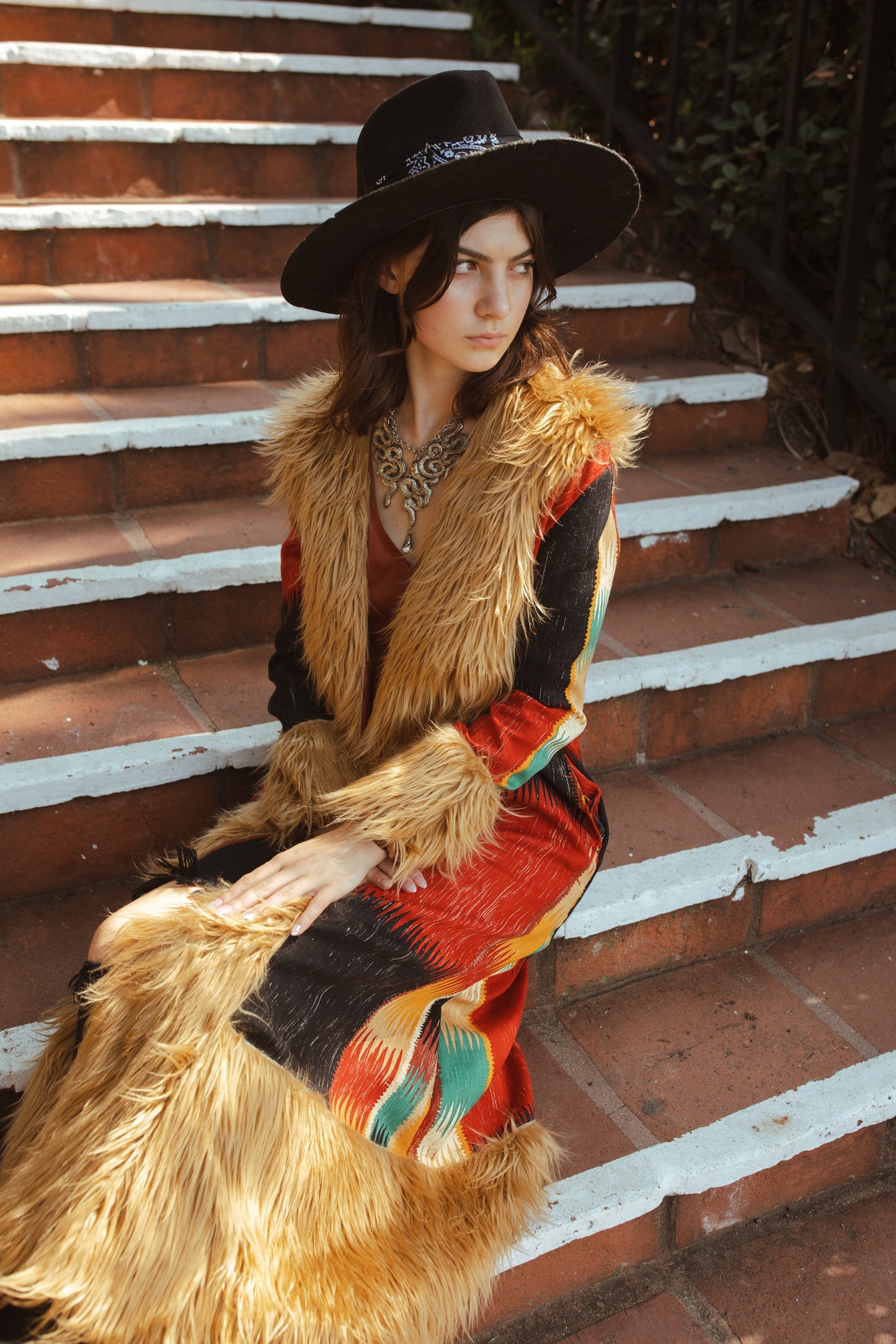 Long, penny lane style trench coat fashioned from a thick, abstract modernist colorblock print fabric featuring red, teal, yellow, black, and beige. Embellished with long tan faux fur along collar, lapel, cuffs, and hem. Retro bohemian color field art in style.