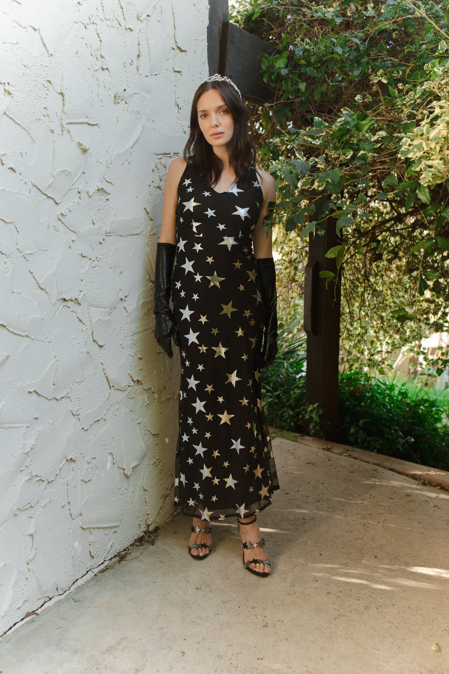 A magical form-fitting mermaid maxi dress features a cutout at mid-back. With a V-neckline and ankle hem, it is crafted from a soft black mesh with metallic silver foil star print and bamboo blend jersey lining.