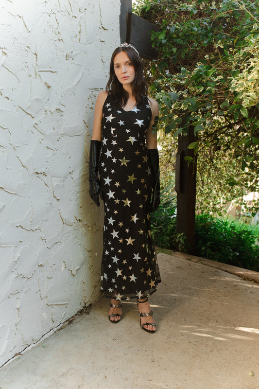A magical form-fitting mermaid maxi dress features a cutout at mid-back. With a V-neckline and ankle hem, it is crafted from a soft black mesh with metallic silver foil star print and bamboo blend jersey lining.