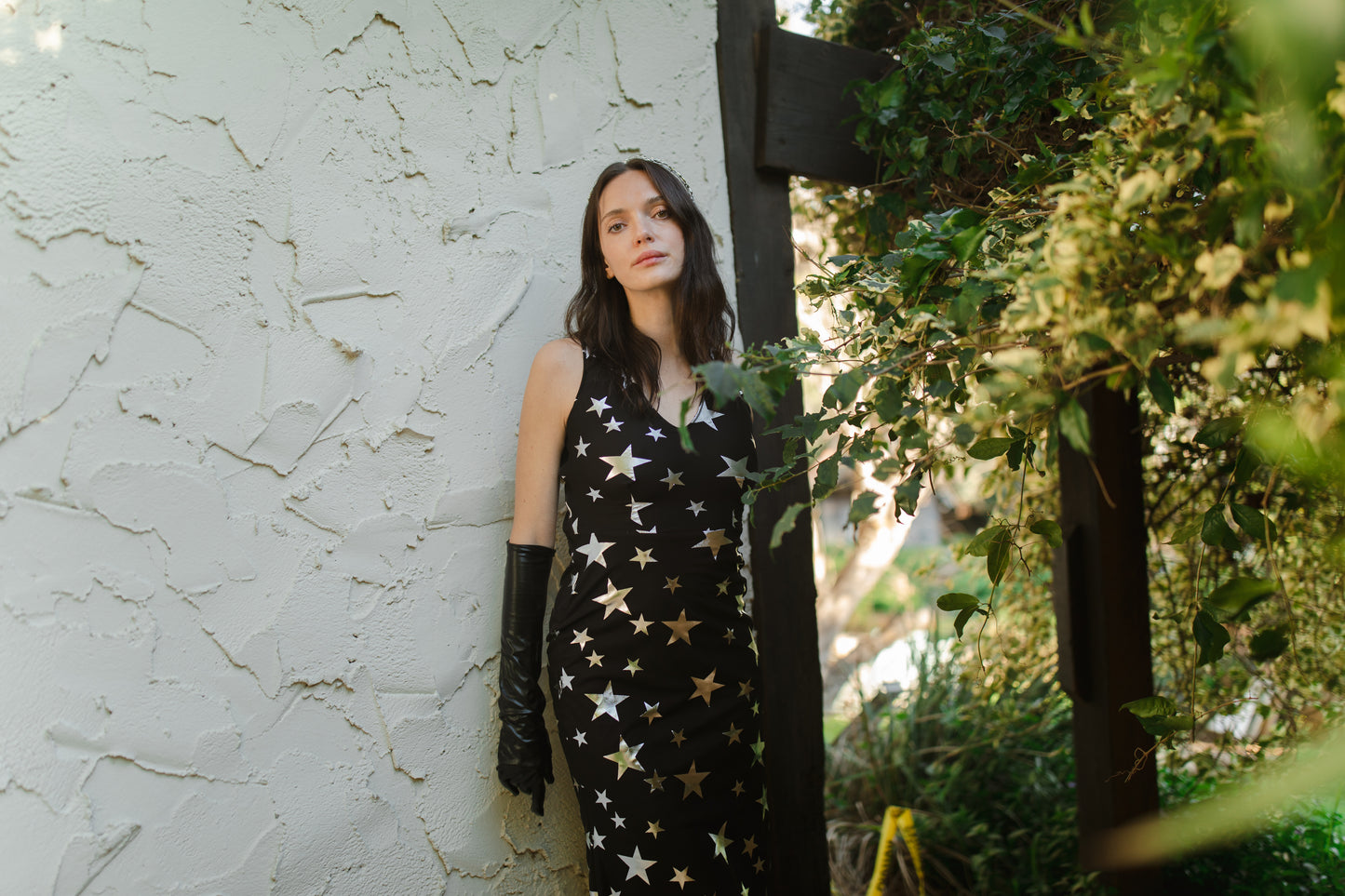 A magical form-fitting mermaid maxi dress features a cutout at mid-back. With a V-neckline and ankle hem, it is crafted from a soft black mesh with metallic silver foil star print and bamboo blend jersey lining.