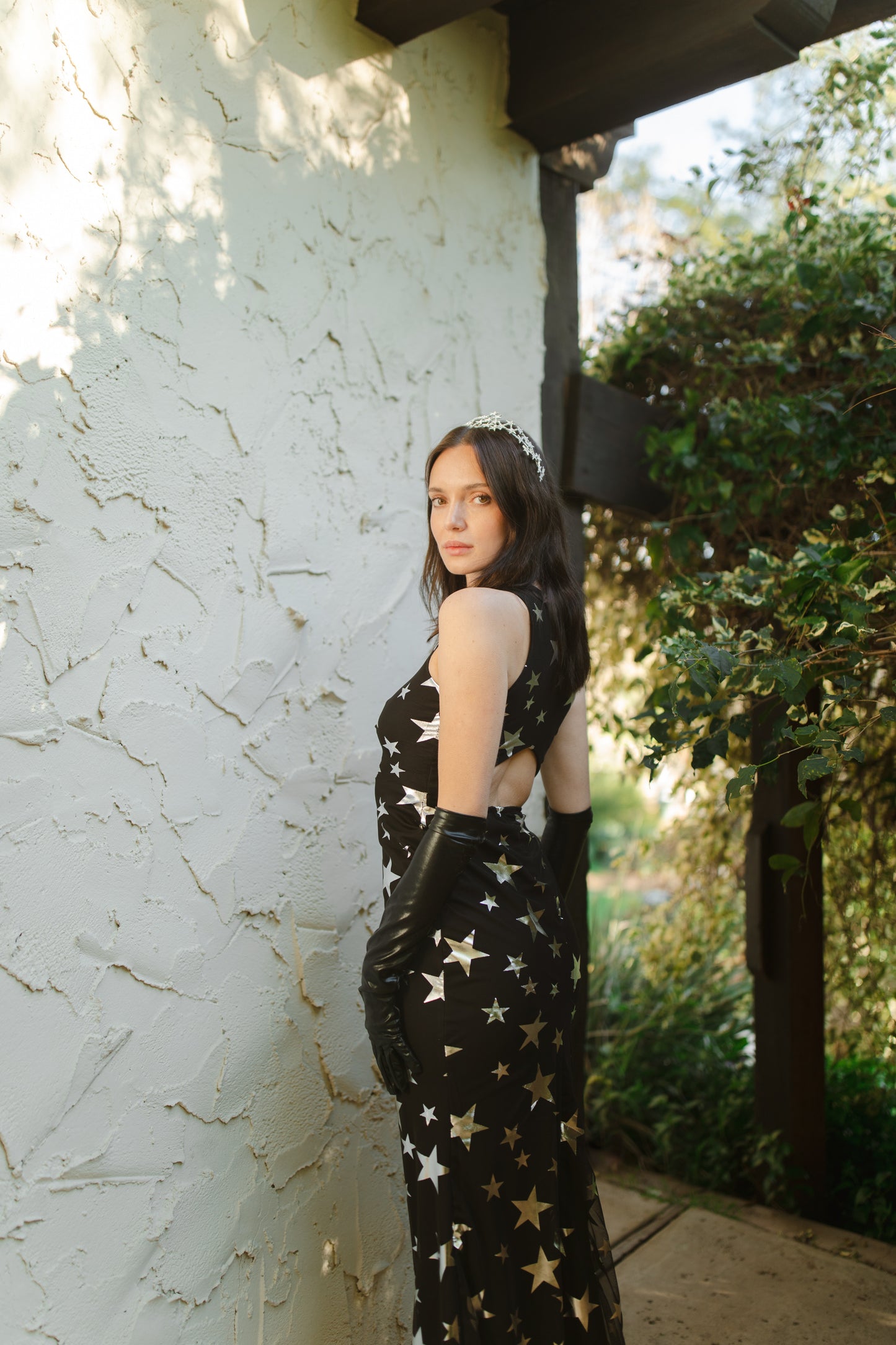 A magical form-fitting mermaid maxi dress features a cutout at mid-back. With a V-neckline and ankle hem, it is crafted from a soft black mesh with metallic silver foil star print and bamboo blend jersey lining.