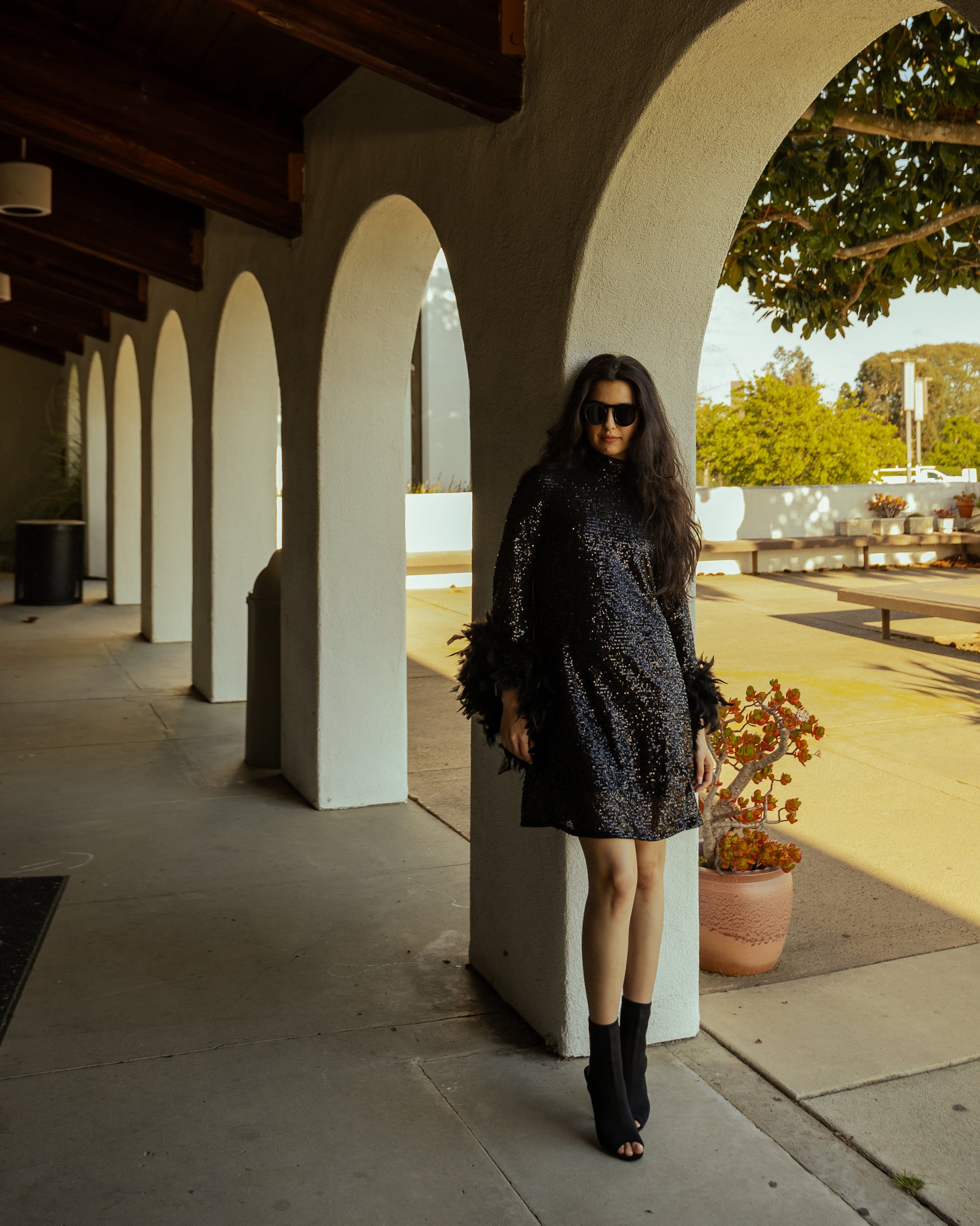 This shimmering black sequin mod mini dress has it all - glittering sequins, delicate mock neck, and long bell sleeves cuffed with black feathers