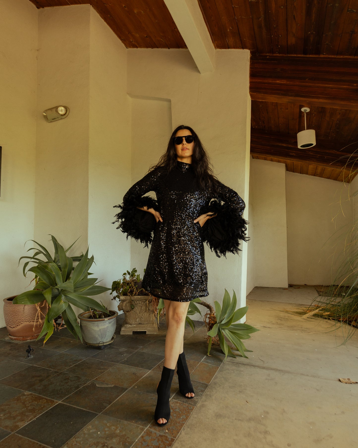 This shimmering black sequin mod mini dress has it all - glittering sequins, delicate mock neck, and long bell sleeves cuffed with black feathers