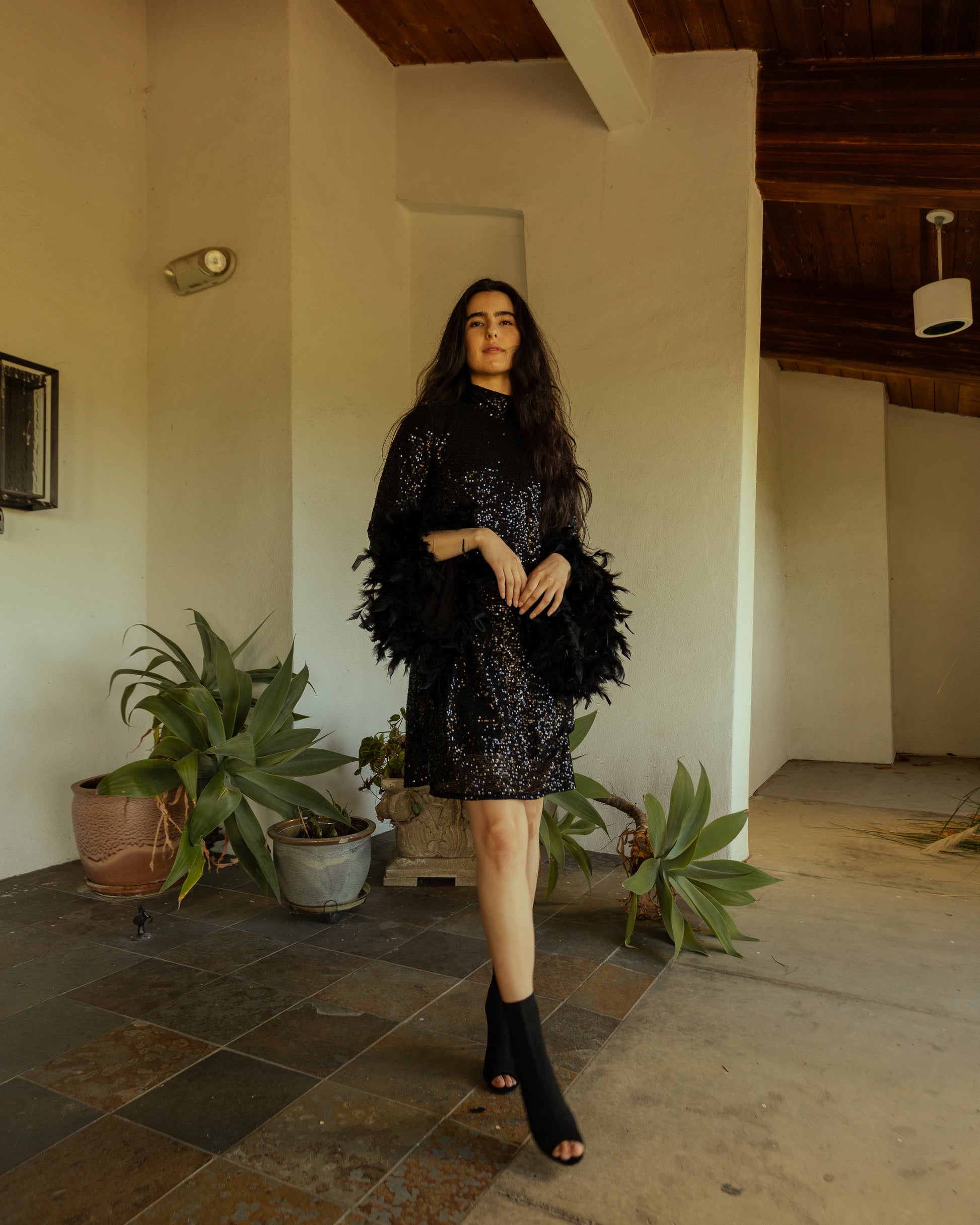 This shimmering black sequin mod mini dress has it all - glittering sequins, delicate mock neck, and long bell sleeves cuffed with black feathers