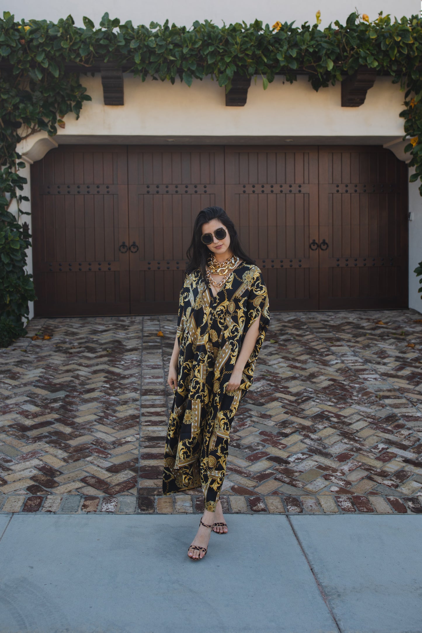 Opaque black caftan dress featuring yellow gold ornamental filigree patterned design. Featuring a deep v-neckline, short batwing sleeves, and an ankle-length hem. This caftan is a voluminous garment that gives a flowy silhouette that drapes beautifully on all shapes.