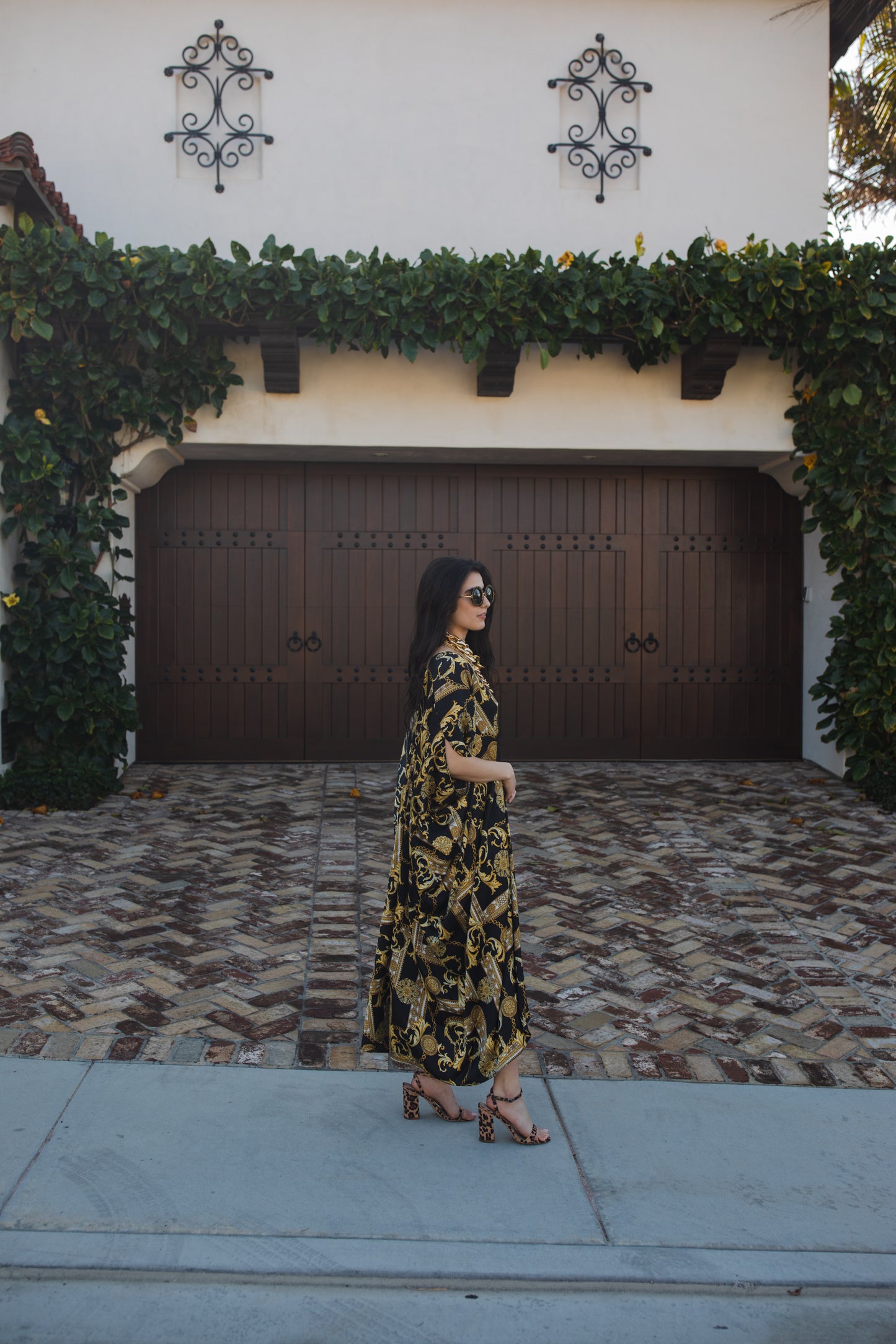 Opaque black caftan dress featuring yellow gold ornamental filigree patterned design. Featuring a deep v-neckline, short batwing sleeves, and an ankle-length hem. This caftan is a voluminous garment that gives a flowy silhouette that drapes beautifully on all shapes.
