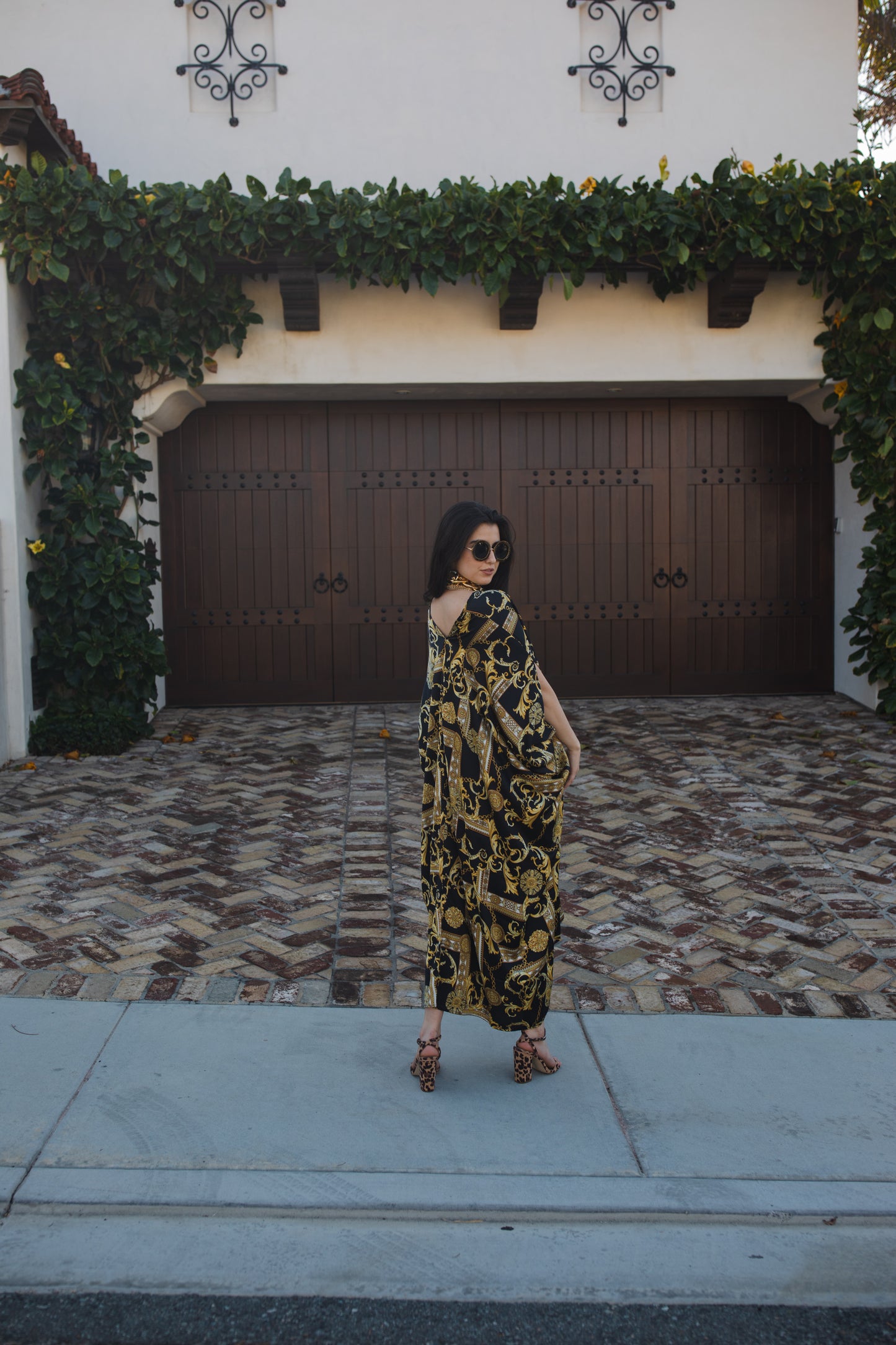 Opaque black caftan dress featuring yellow gold ornamental filigree patterned design. Featuring a deep v-neckline, short batwing sleeves, and an ankle-length hem. This caftan is a voluminous garment that gives a flowy silhouette that drapes beautifully on all shapes.