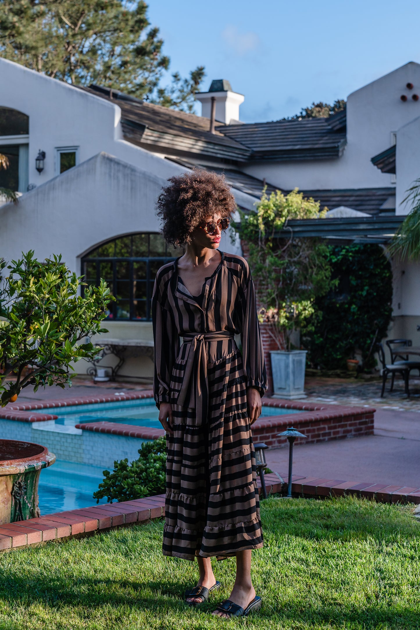 A coffee colored striped ruffled maxi dress. Featuring thick black and brown café stripes, long sleeves, ankle hem, full length button down in front, and optional belt to cinch the waist.
