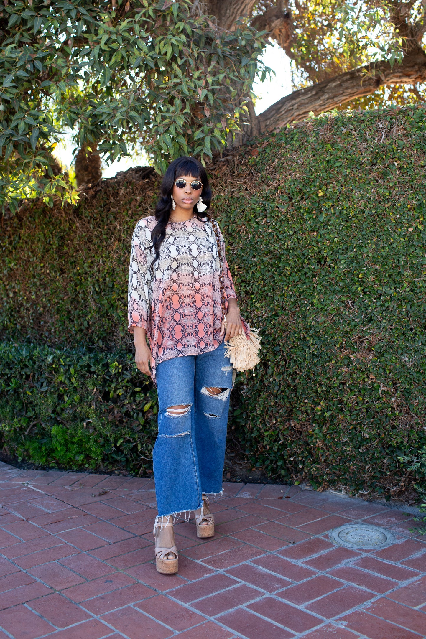 This orange and turquoise snakeskin print top features a wide boat neckline, gracefully exposing the collarbone, while batwing sleeves extend from the shoulders, flowing freely like a soft cascade of fabric. The waist-length hem adds a touch of structure, making it versatile for styling.