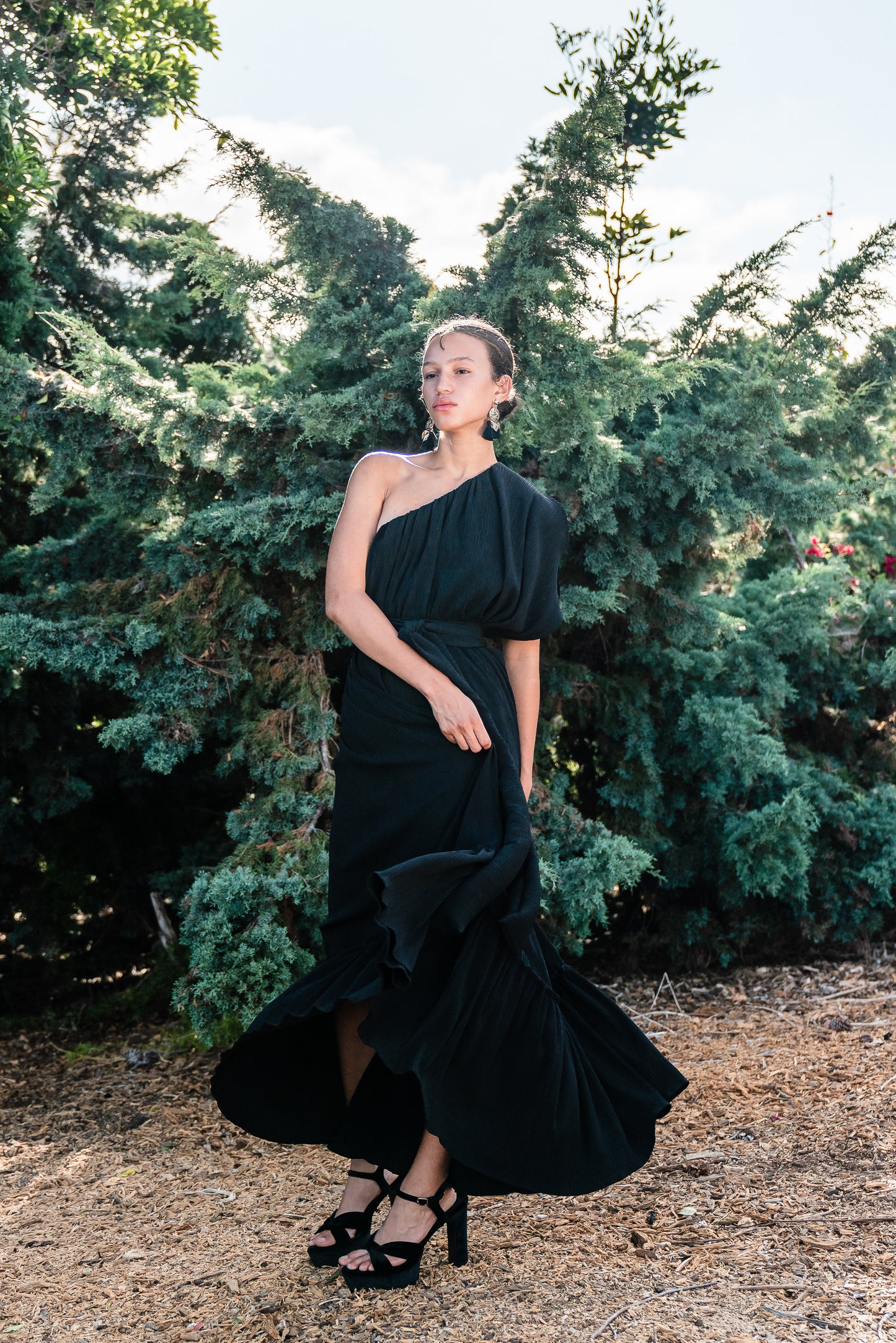 Effortlessly elegant, the Black Diamond Pleated Maxi Dress features a flattering one shoulder design with a long Obi style belt. The pleated details and shimmering sequins add texture and movement, while the flared silhouette and ruffle hem create a feminine and sophisticated look.