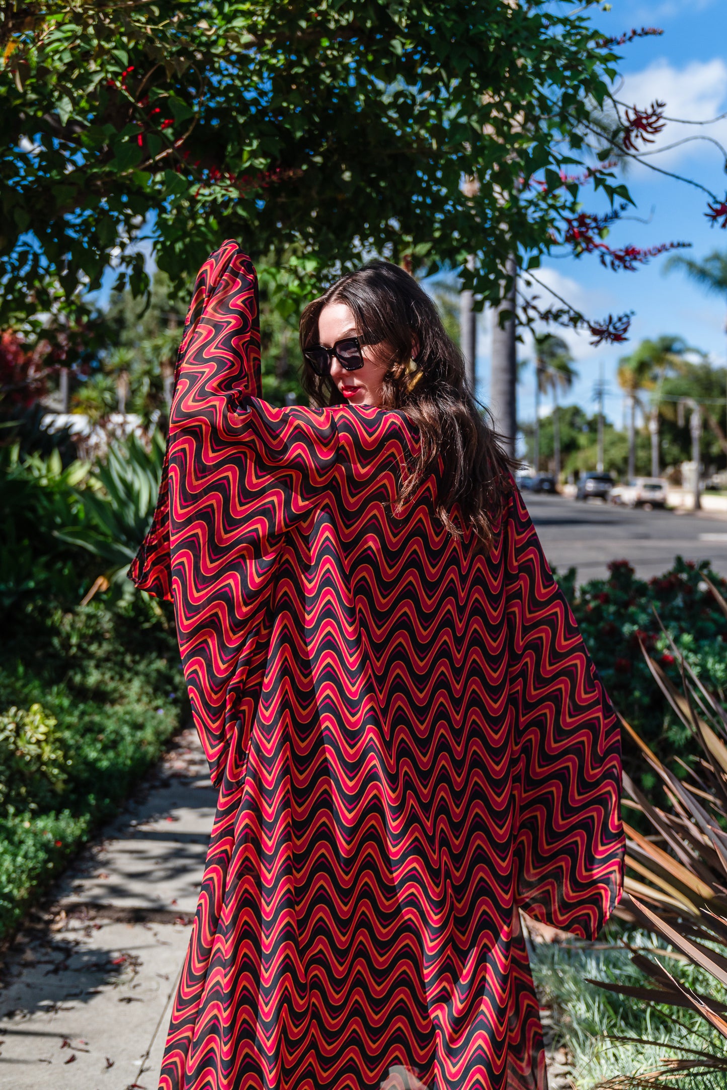 This Kimono features a futuristic spiral print in striking black and red, with a pop of orange for a modern and elegant touch.