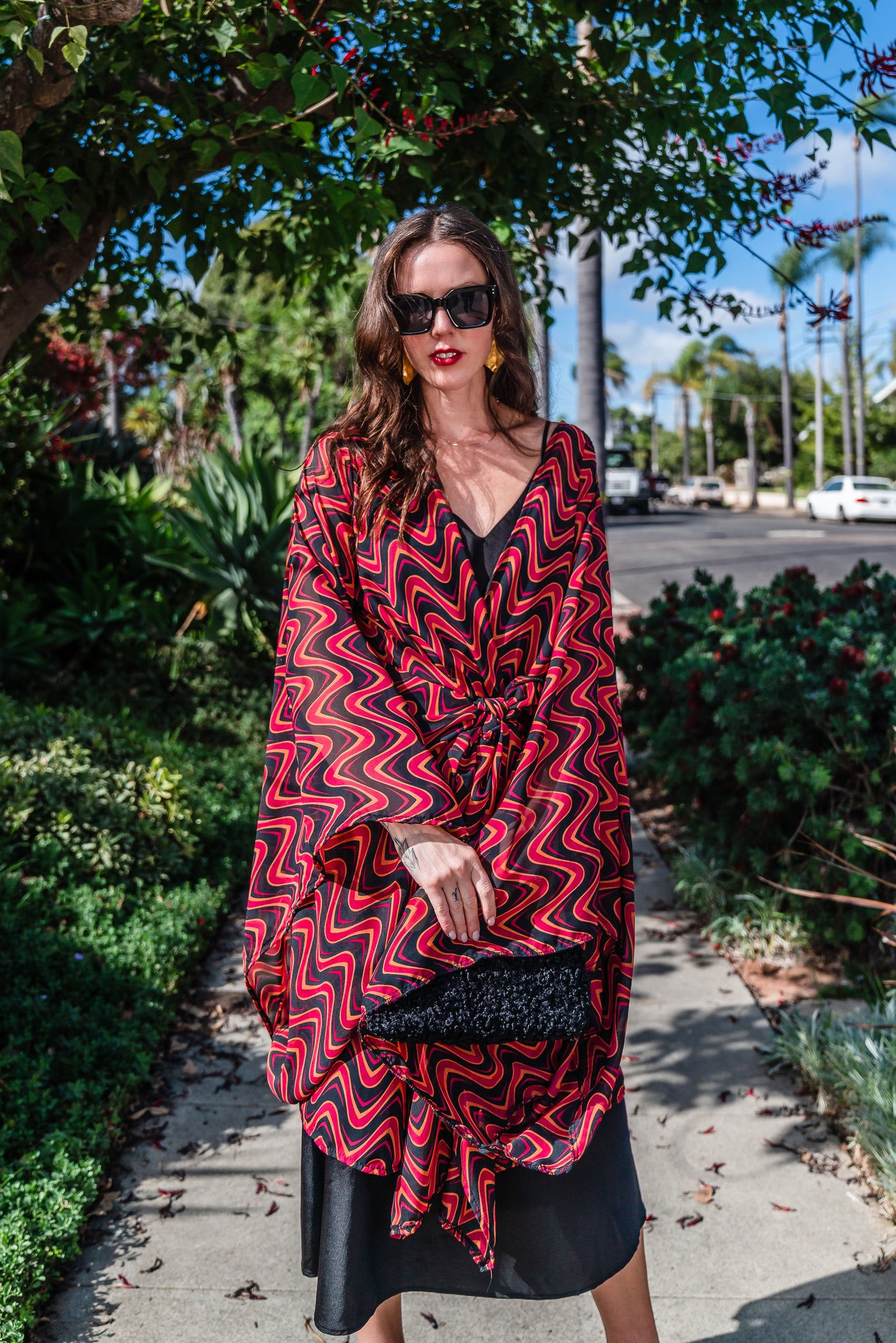 This Kimono features a futuristic spiral print in striking black and red, with a pop of orange for a modern and elegant touch.