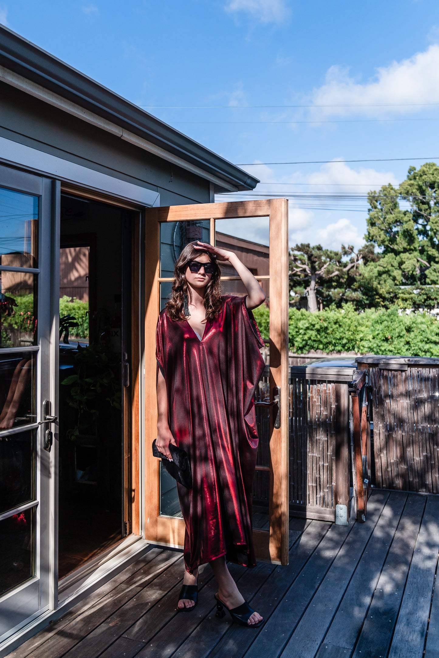 A metallic solid red caftan featuring batwing sleeves, a deep v neckline, and ankle length hem.
